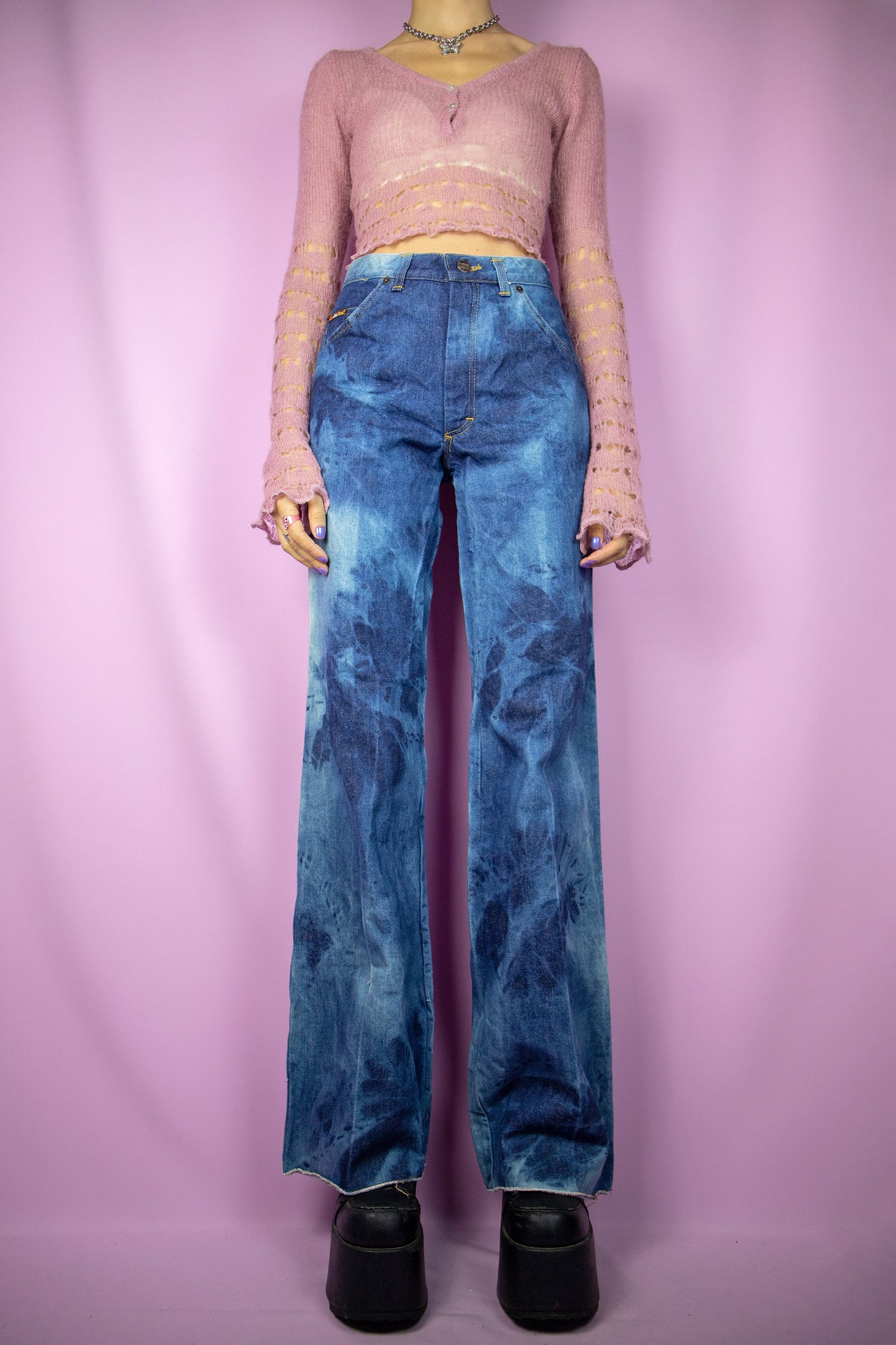The Vintage 90’s Bleached Wide Jeans are high-waisted, tie-dye bleached wide-leg pants with pockets and a raw hem. Ideal for festivals, raves, and clubbing, these denim trousers capture the cyber millennium style of the 1990s.