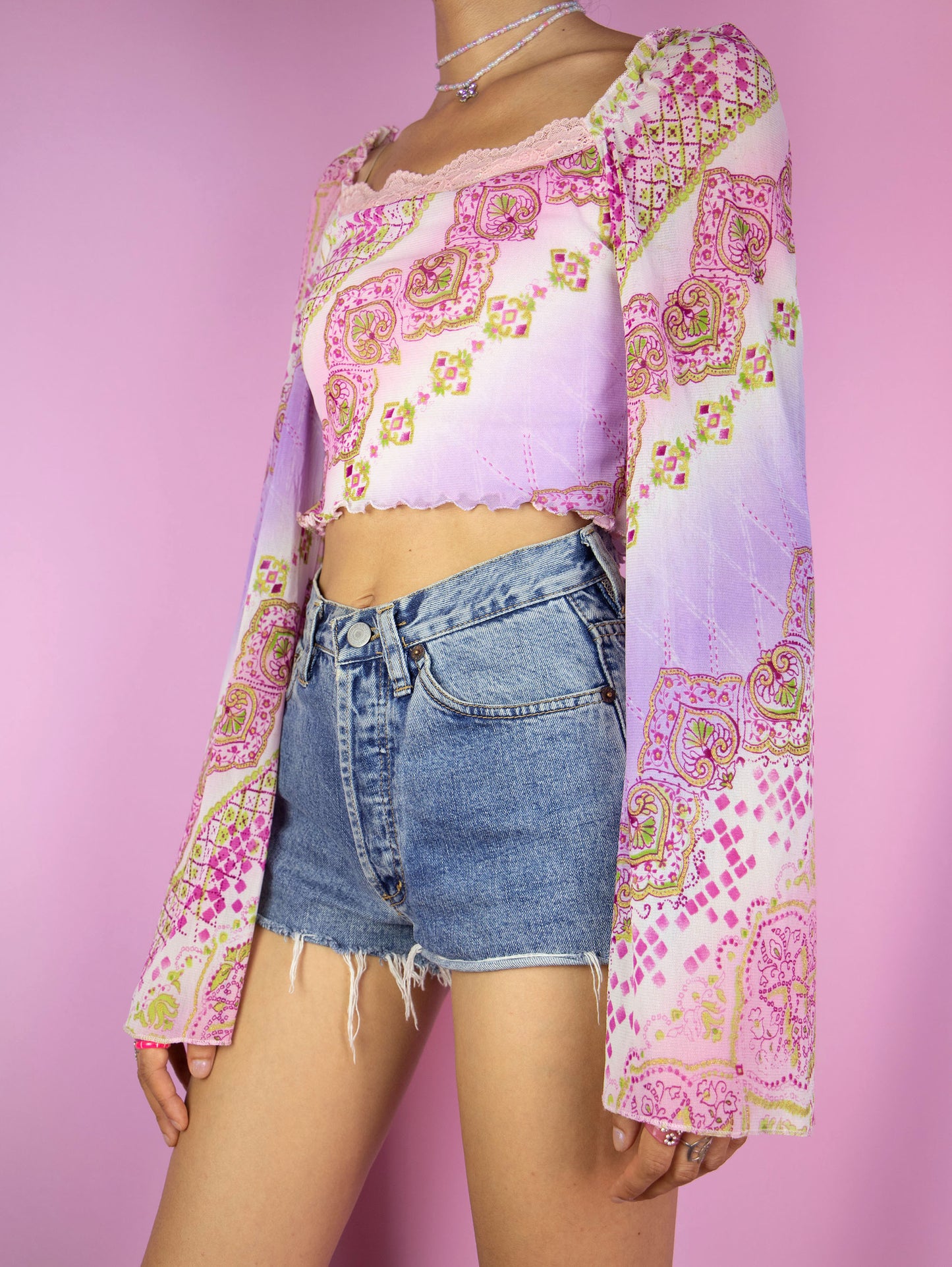 The Y2K Fairy Pink Mesh Top is a vintage abstract floral paisley graphic semi-sheer mesh crop top with bell sleeves and lace details. Boho romantic 2000s cyber coquette shirt.