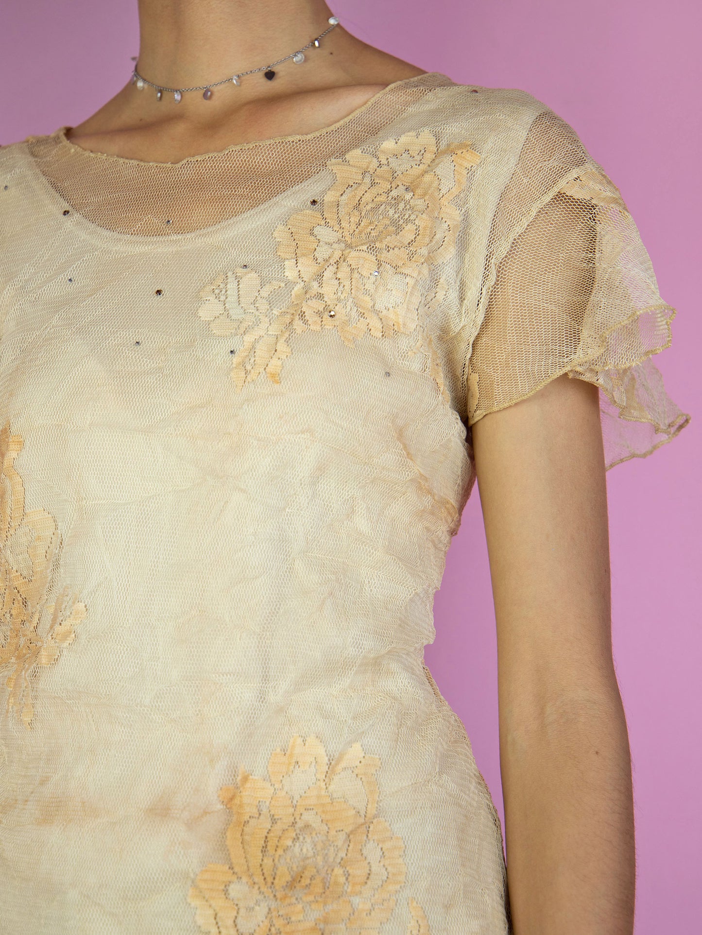 The Y2K Beige Mesh Sheer Top is a vintage short-sleeve, light brown semi-sheer mesh top adorned with delicate floral tulle and rhinestones. Romantic coquette 2000s fairy grunge shirt.