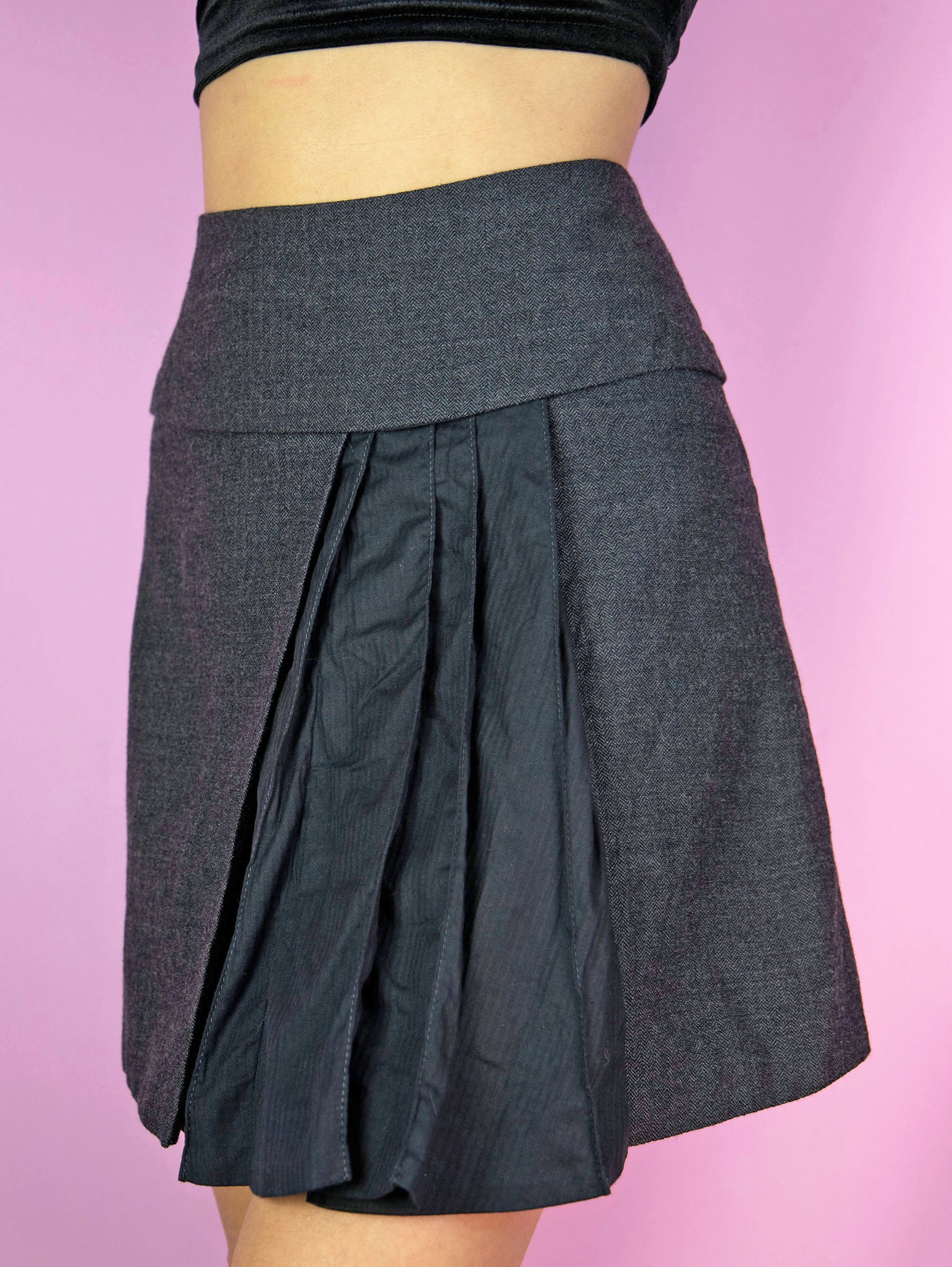 The Vintage Y2K Gray Asymmetric Mini Skirt is a vintage gray wool blend skirt with black pleated detailing and a back zipper closure. Fairy grunge 2000s subversive knit mini skirt.