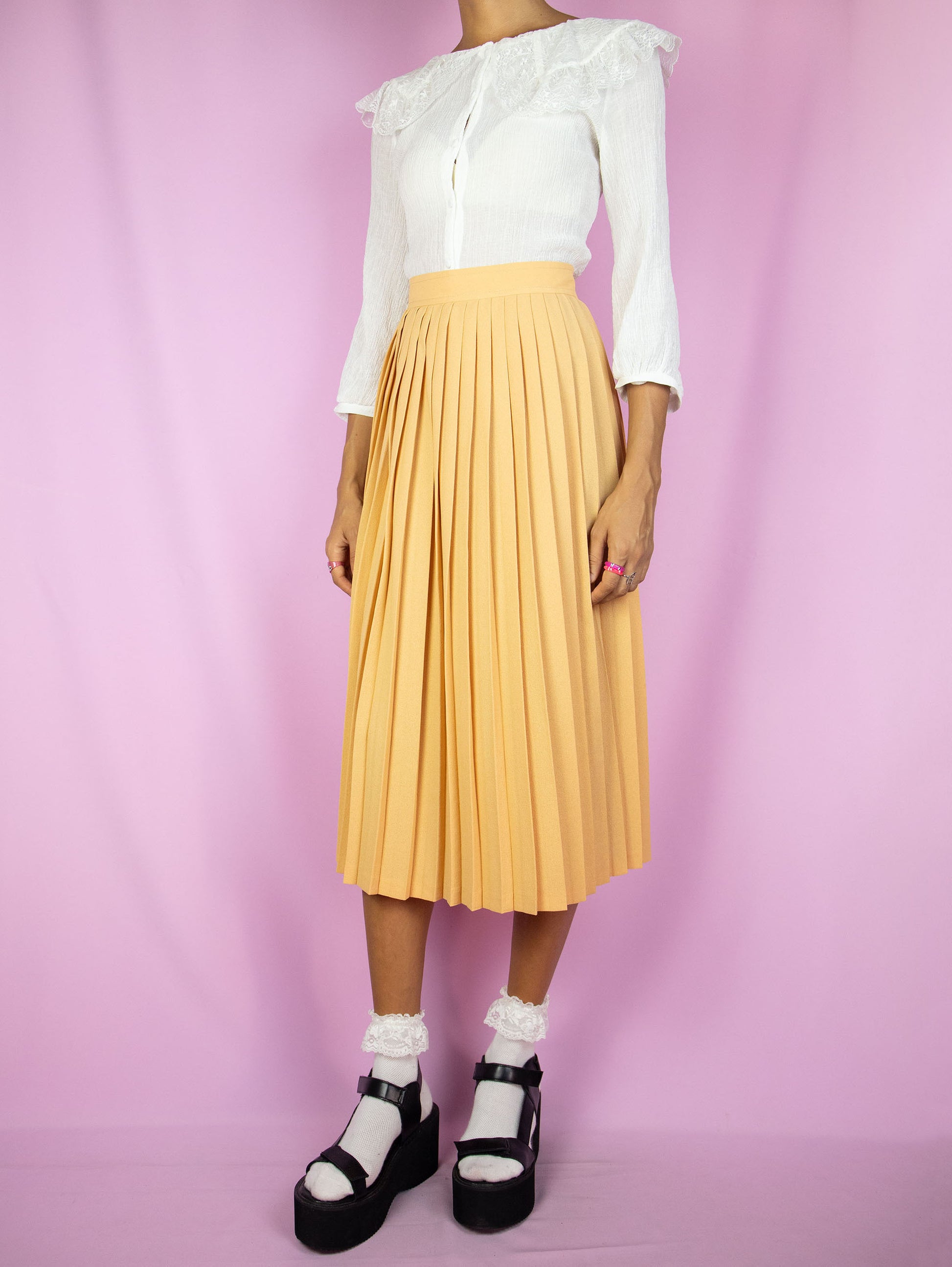 The Vintage 80s Orange Pleated Midi Skirt is a pastel light orange skirt with a back zipper closure. Classic preppy 1980s skirt.
