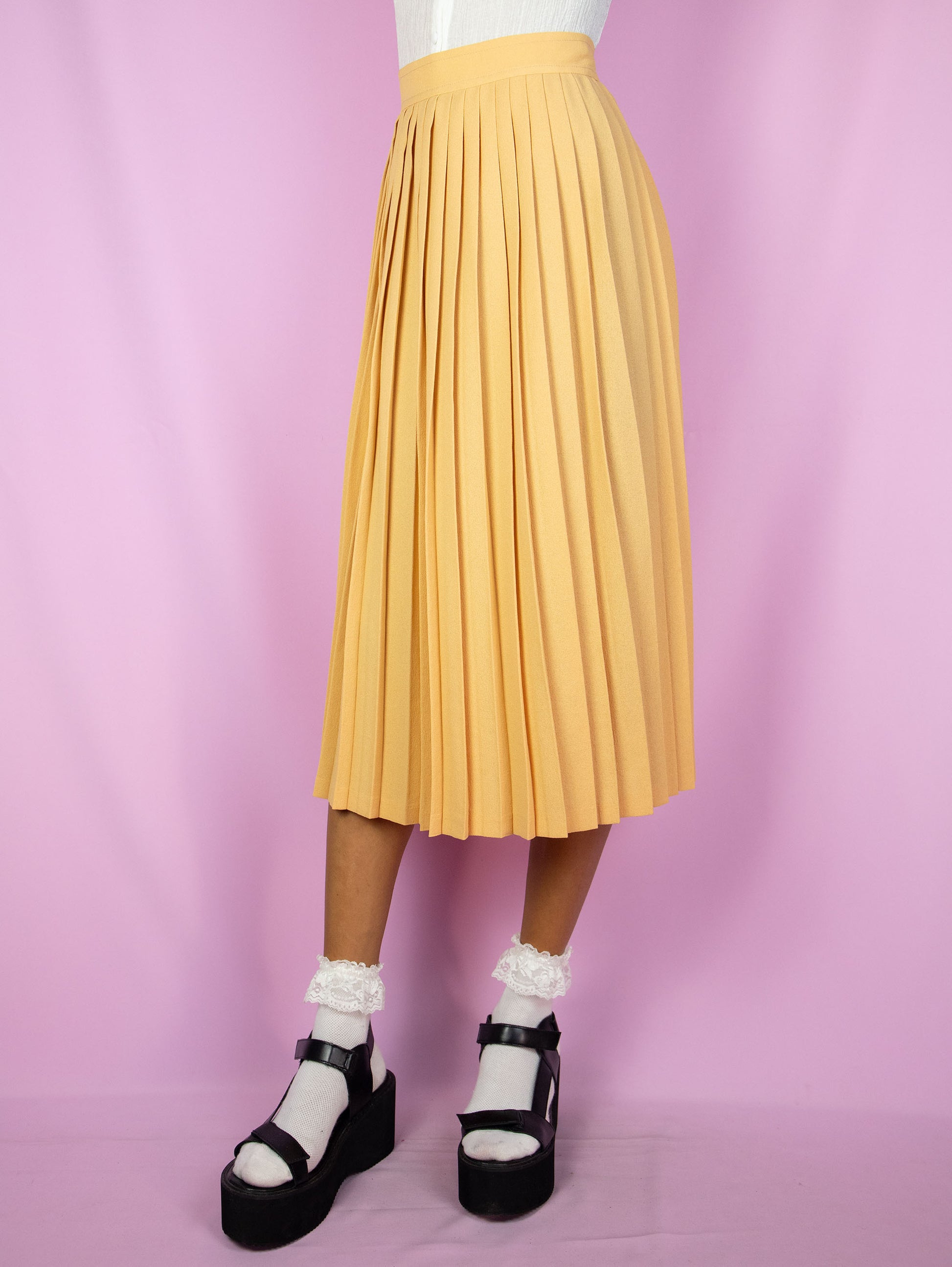 The Vintage 80s Orange Pleated Midi Skirt is a pastel light orange skirt with a back zipper closure. Classic preppy 1980s skirt.
