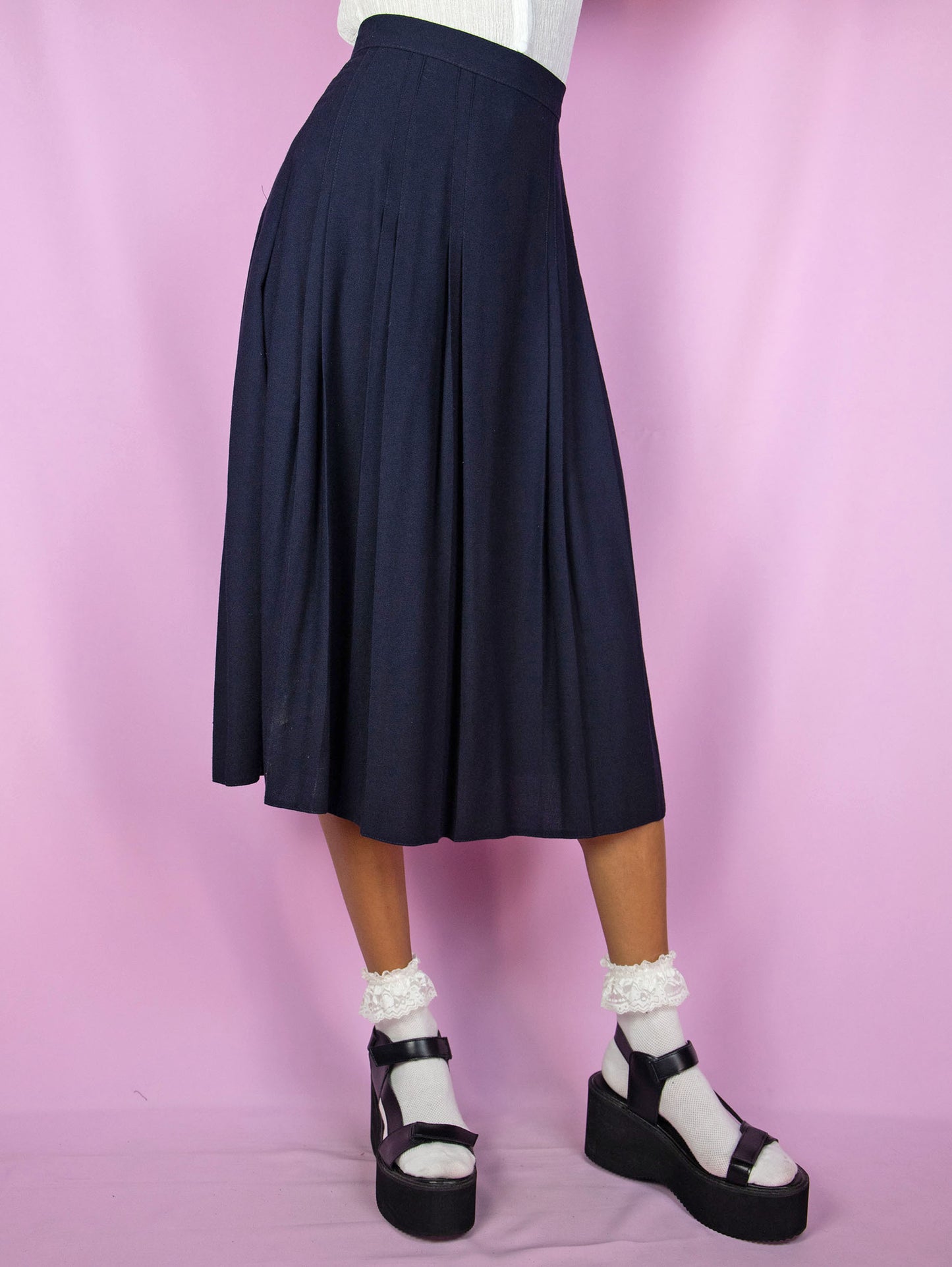 The Vintage 90s Navy Pleated Midi Skirt is a dark blue skirt with a side zipper closure. Classic preppy 1990s skirt.