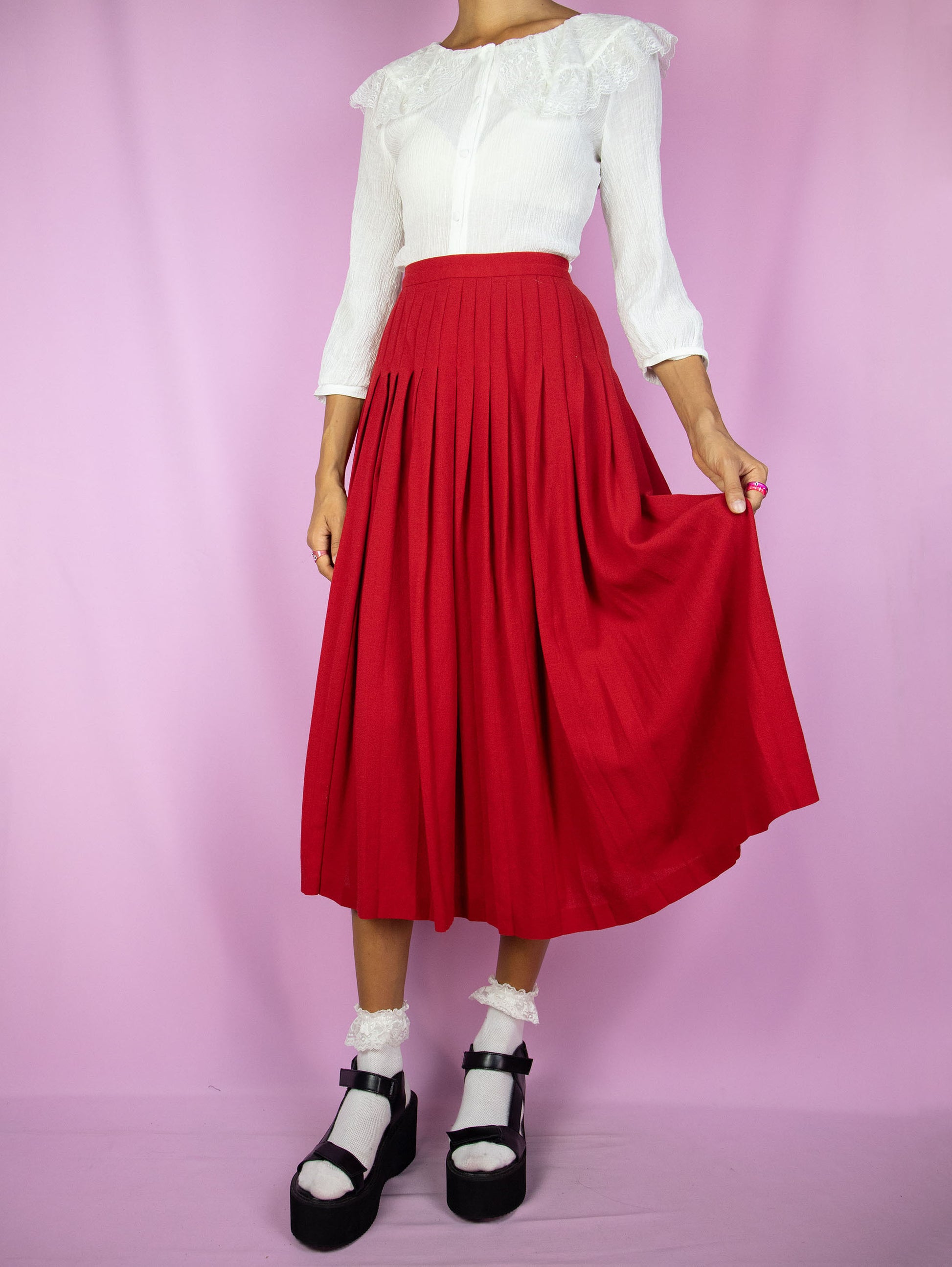 The Vintage 80s Red Wool Pleated Skirt is a midi skirt made of pure new wool featuring a side button closure. Classic preppy 1980s skirt.