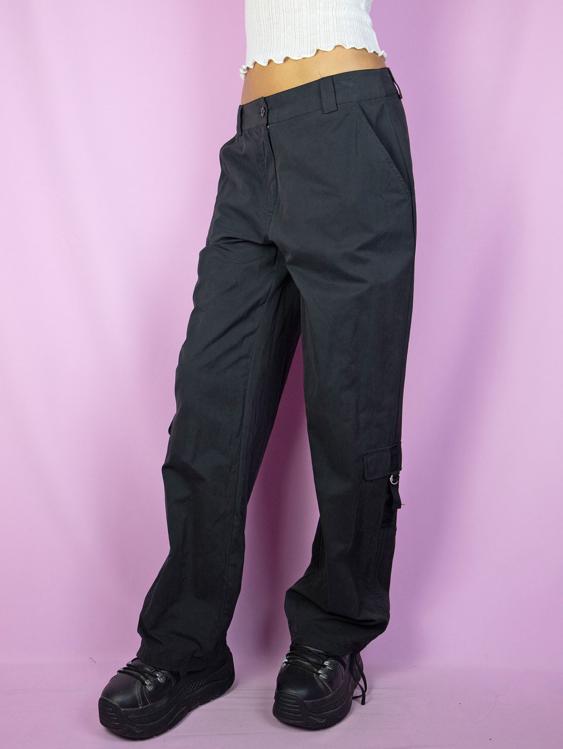 The Y2K Black Cargo Pants are vintage mid-rise wide pants with pockets and a front zipper closure. Cyber grunge 2000s utility trousers.