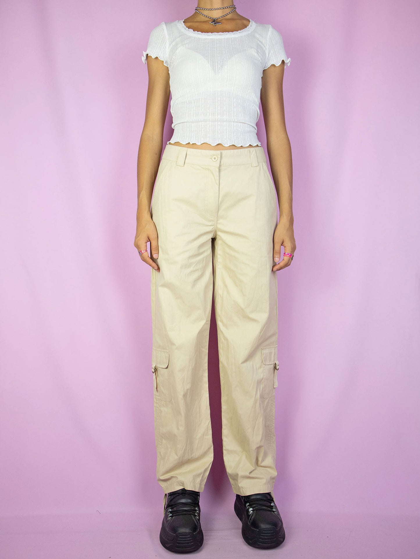 The Y2K Beige Cargo Pants are vintage mid-rise wide pants with pockets and a front zipper closure. Cyber grunge 2000s utility trousers.