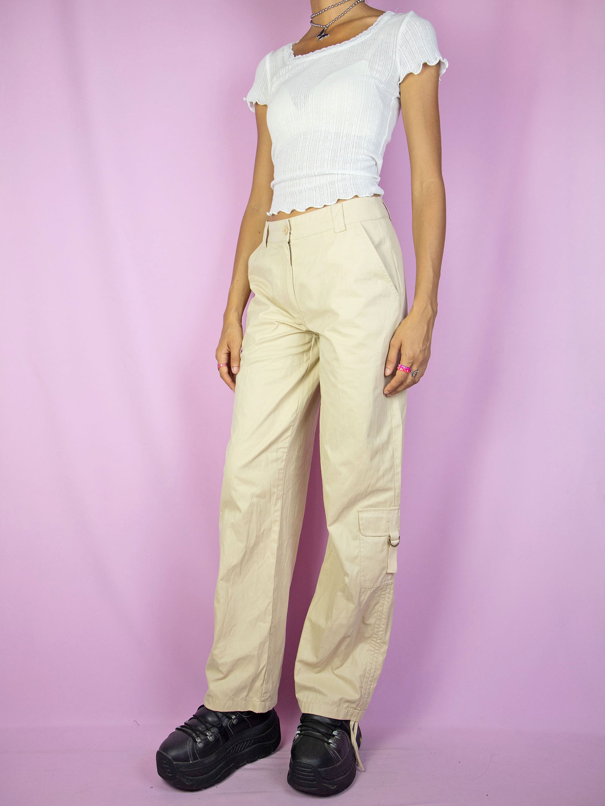 The Y2K Beige Cargo Pants are vintage mid-rise wide pants with pockets and a front zipper closure. Cyber grunge 2000s utility trousers.