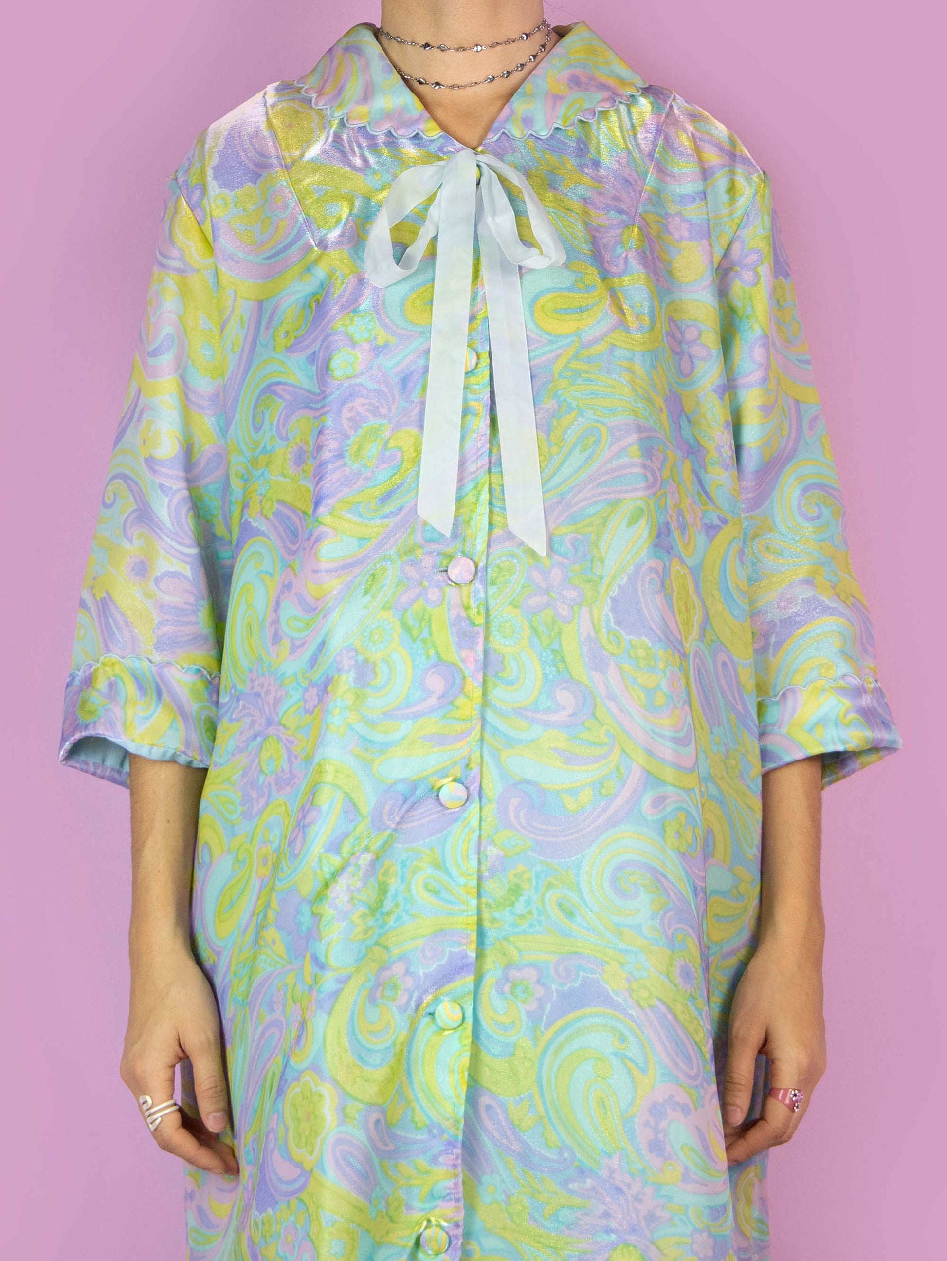 The Vintage 70s Pastel Duster Robe is a multicolored pastel robe with an abstract floral paisley print, half sleeves, button closure, and a tie collar. Romantic 1970s boho peignoir jacket.