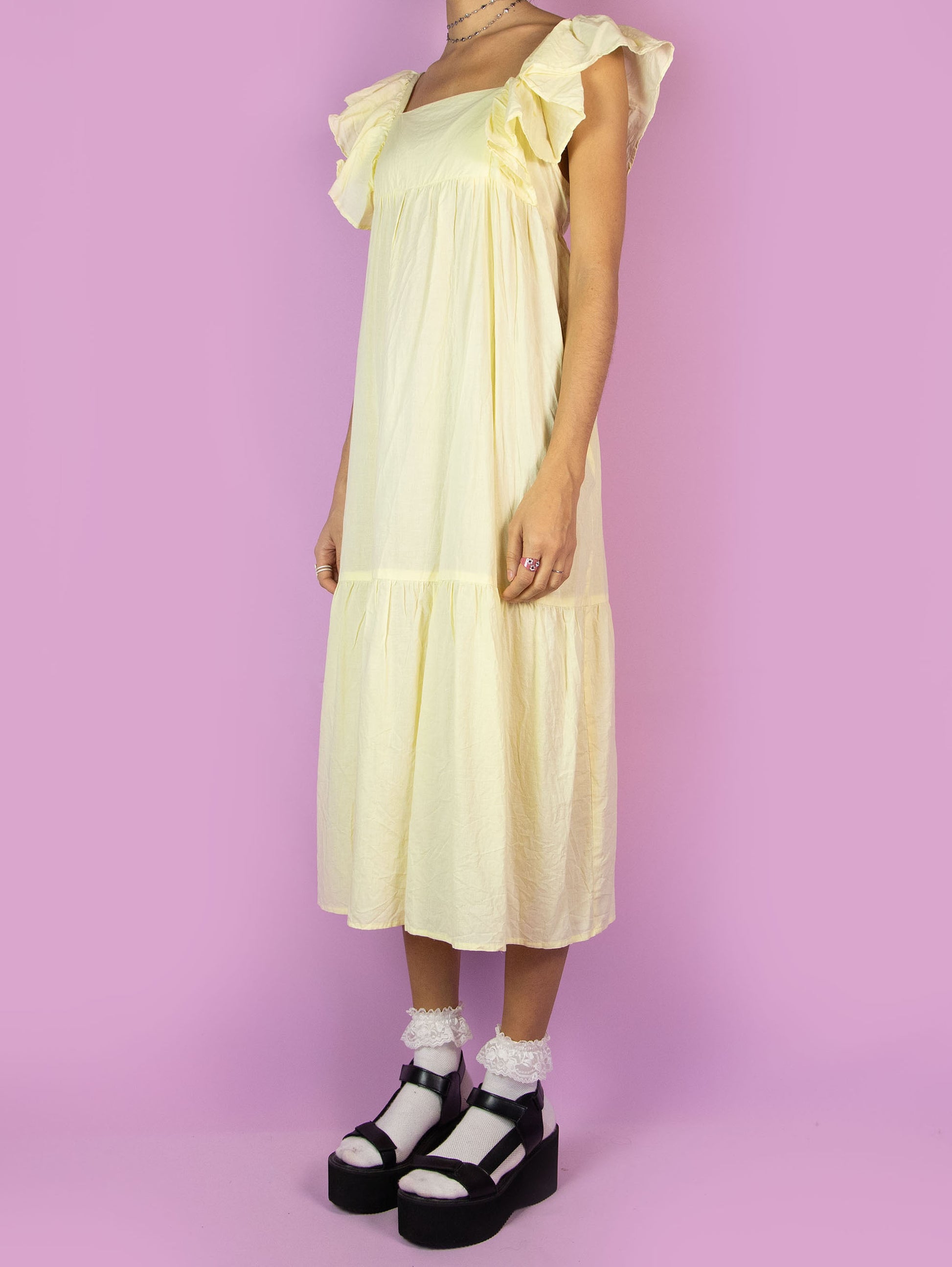 The Y2K Boho Tiered Midi Dress is a vintage light pastel yellow dress with a slightly transparent tiered design and ruffles on the straps. Summer 2000s beach cover up maxi dress.