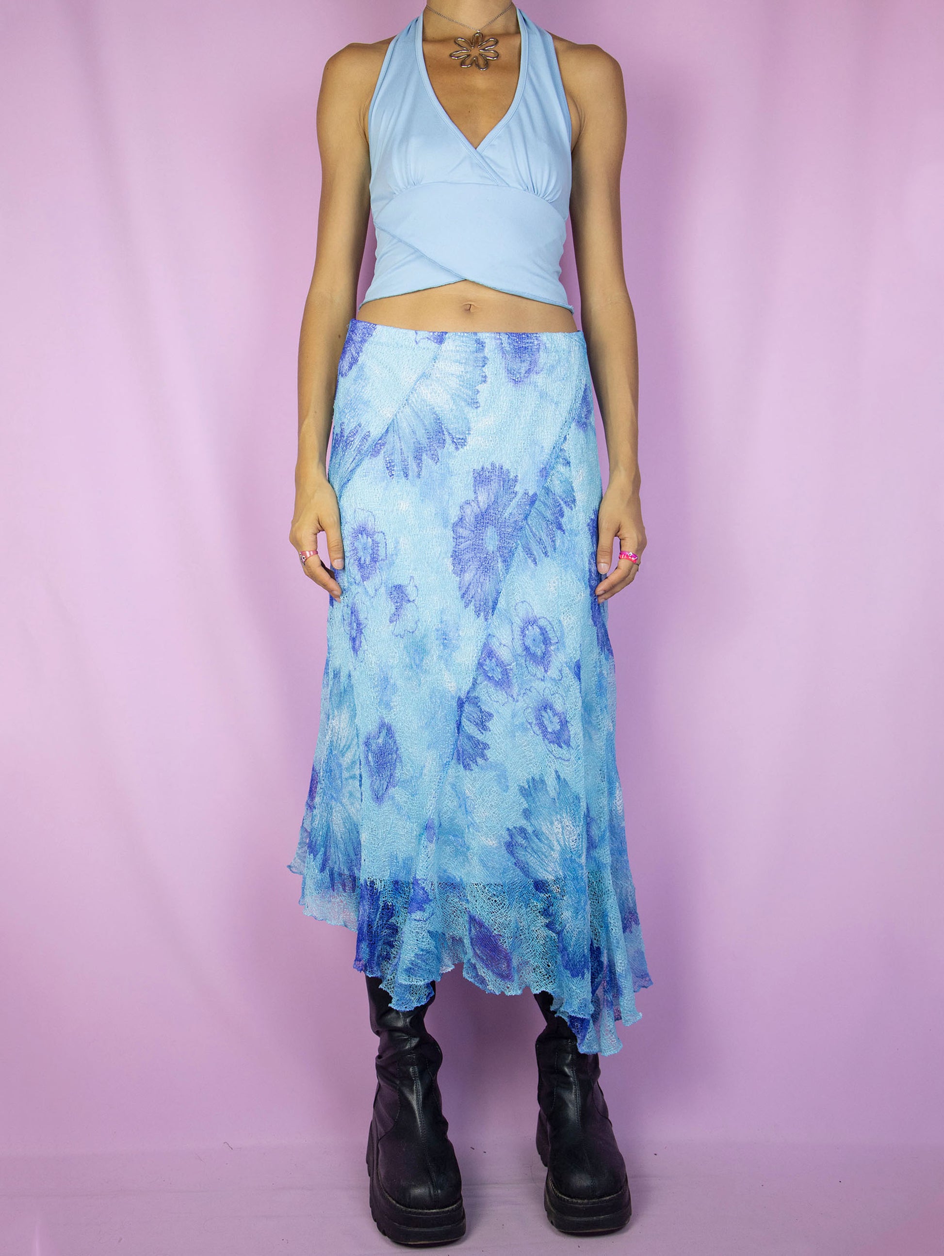 The Y2K Blue Mesh Midi Skirt is a vintage 2000s piece featuring a floral print, an asymmetrical hem, an elastic waistband, and a lightweight semi-sheer overlay. Perfect for adding a whimsical touch to your spring or summer wardrobe.