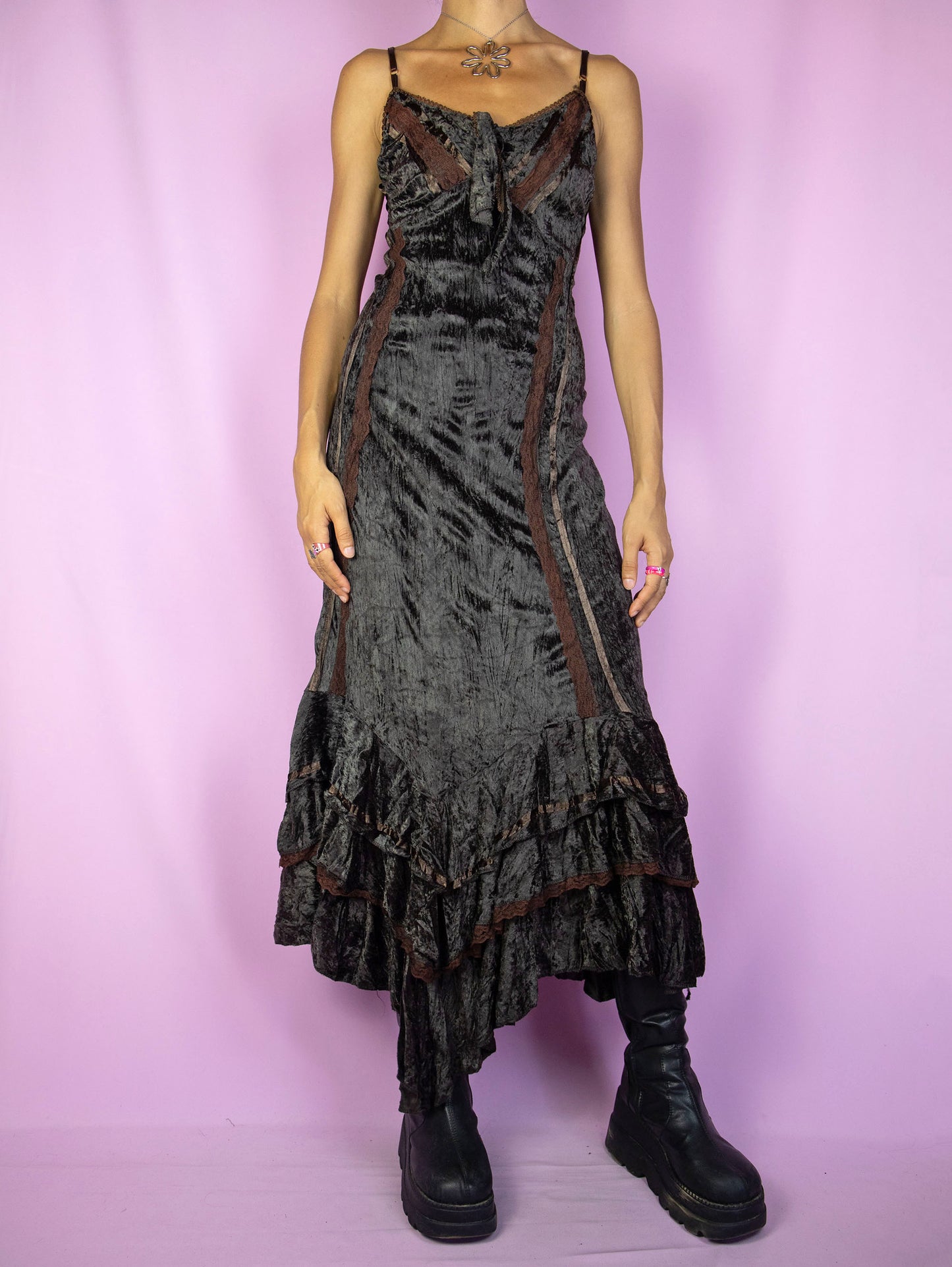 The Vintage 90s Brown Velvet Maxi Dress is a dark brown dress with adjustable straps, a tied v-neck, asymmetrical ruffled hem, lace details, and a lace-up tied back. Fairy grunge whimsygoth style 1990s evening party midi dress.