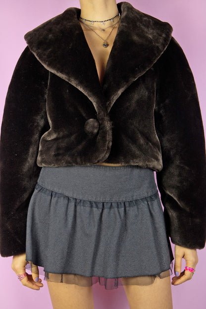 The Vintage 90’s Brown Faux Fur Cropped Jacket is a dark brown faux fur bolero jacket featuring a collar and a secure hook closure. This charming statement piece originates from the 1990s.