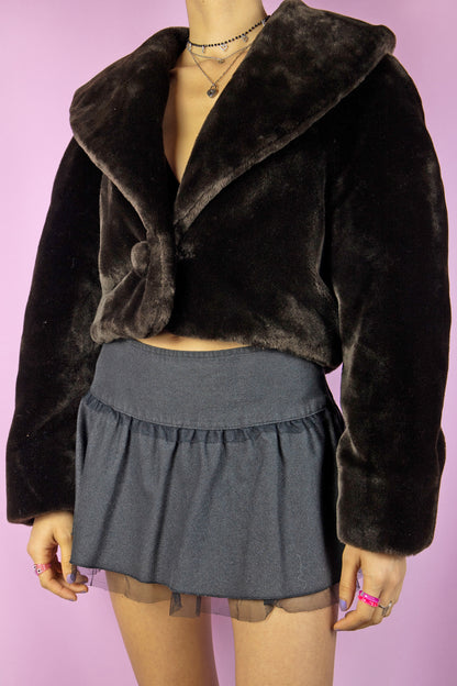 The Vintage 90’s Brown Faux Fur Cropped Jacket is a dark brown faux fur bolero jacket featuring a collar and a secure hook closure. This charming statement piece originates from the 1990s.