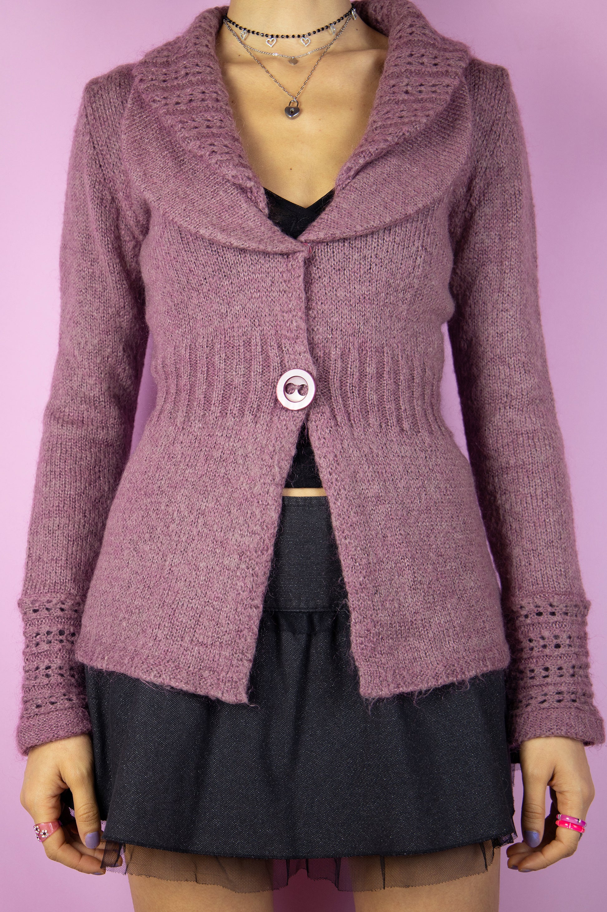 The Y2K Pink Collar Cardigan is a vintage 2000s sweater featuring a cozy, knitted fabric in a soft mauve hue. It has a wide double collar, a two-button closure, and delicate knit detailing on the sleeves. Perfect for a romantic, casual look, this cardigan adds a touch of warmth to any outfit.