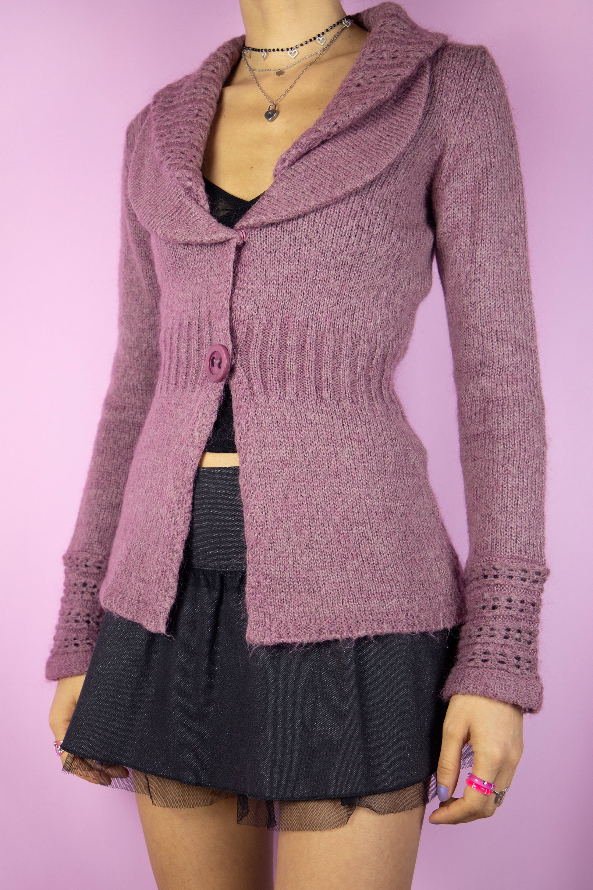 The Y2K Pink Collar Cardigan is a vintage 2000s sweater featuring a cozy, knitted fabric in a soft mauve hue. It has a wide double collar, a two-button closure, and delicate knit detailing on the sleeves. Perfect for a romantic, casual look, this cardigan adds a touch of warmth to any outfit.