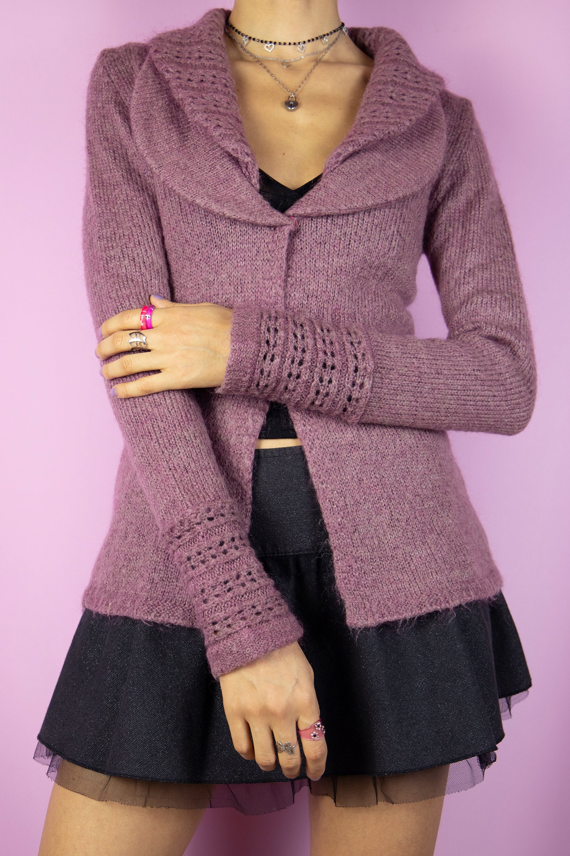 The Y2K Pink Collar Cardigan is a vintage 2000s sweater featuring a cozy, knitted fabric in a soft mauve hue. It has a wide double collar, a two-button closure, and delicate knit detailing on the sleeves. Perfect for a romantic, casual look, this cardigan adds a touch of warmth to any outfit.