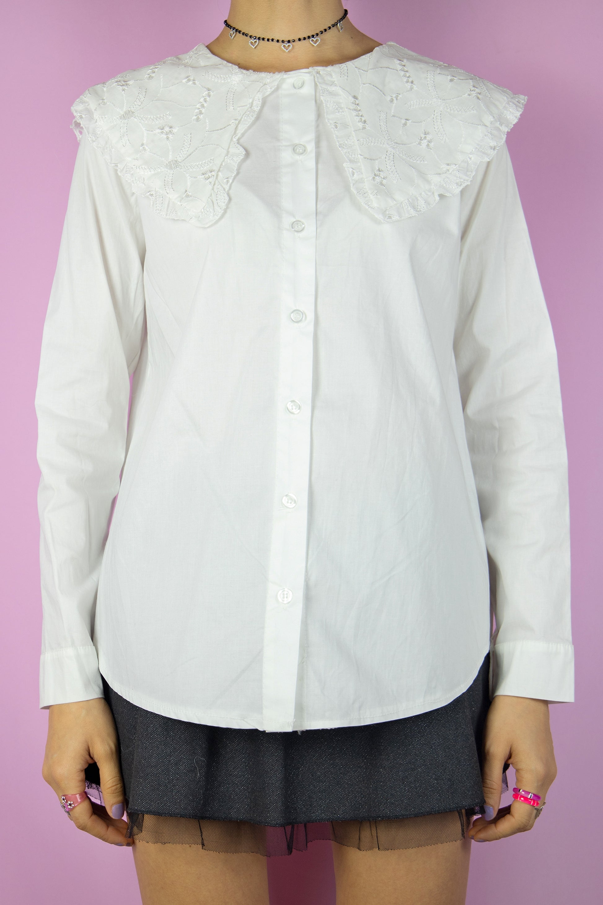The Vintage Y2K White Oversized Collar Blouse is a charming long-sleeve button top featuring a large cream-white collar adorned with embroidered details. This super cute shirt exudes cottage prairie, goth, and grunge vibes, making it a perfect addition to your wardrobe from the 2000s.