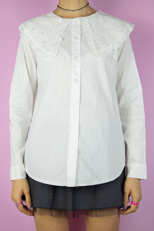 The Y2K White Oversized Collar Blouse is a vintage shirt featuring a large cream-white collar adorned with embroidered details. Country cottage prairie 2000s preppy office blouse.