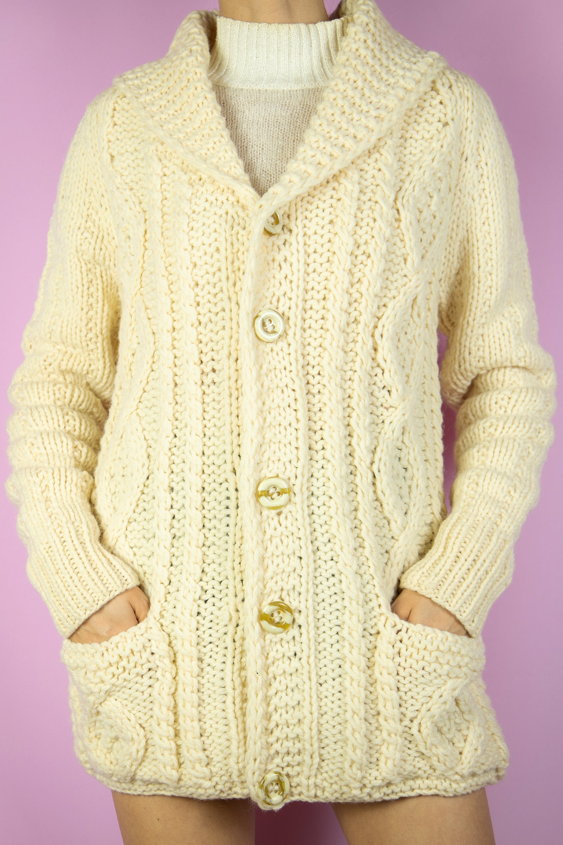The Vintage 90s Beige Wool Knit Cardigan is a cream chunky hand knit wool cardigan with buttons and pockets. Boho retro 1990s winter sweater.