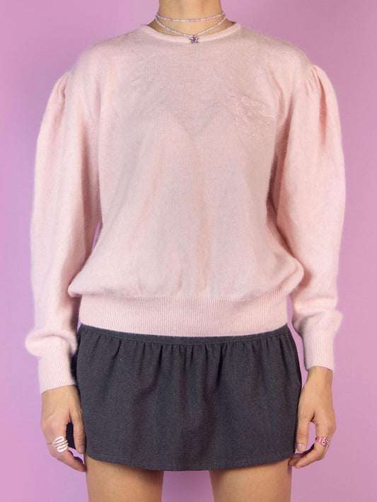 The Vintage 90s Light Pink Knit Sweater is a pastel pink pullover made of a blend of angora wool and acrylic with a button closure at the back. Romantic classic retro 1990s knitted jumper.