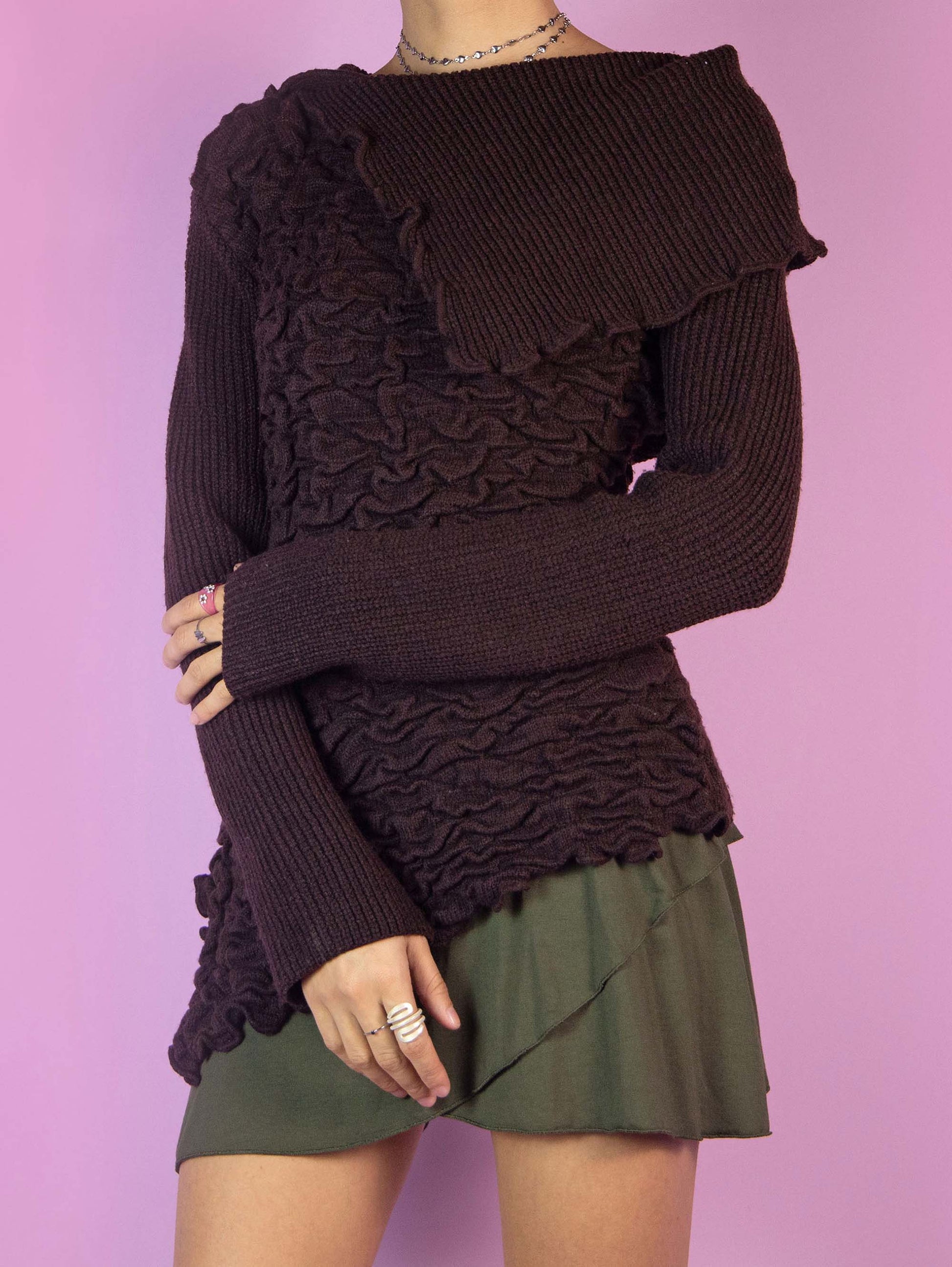 The Y2K Brown Asymmetric Knit Sweater is a vintage dark brown pullover with a pointed asymmetric hem, a textured gathered front, and a collar. Cyber fairy grunge 2000s subversive jumper.