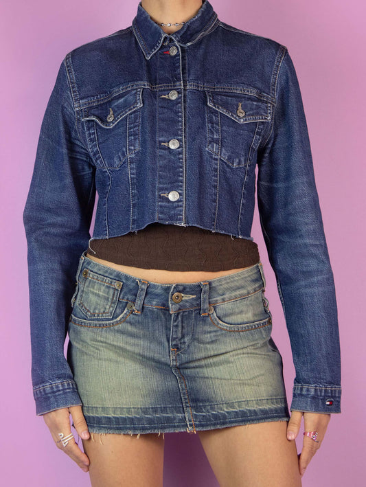 The Y2K Denim Cropped Jacket is a vintage blue denim jacket with collar, buttons, pockets, and a raw hem. Cyber grunge 2000s jean jacket.