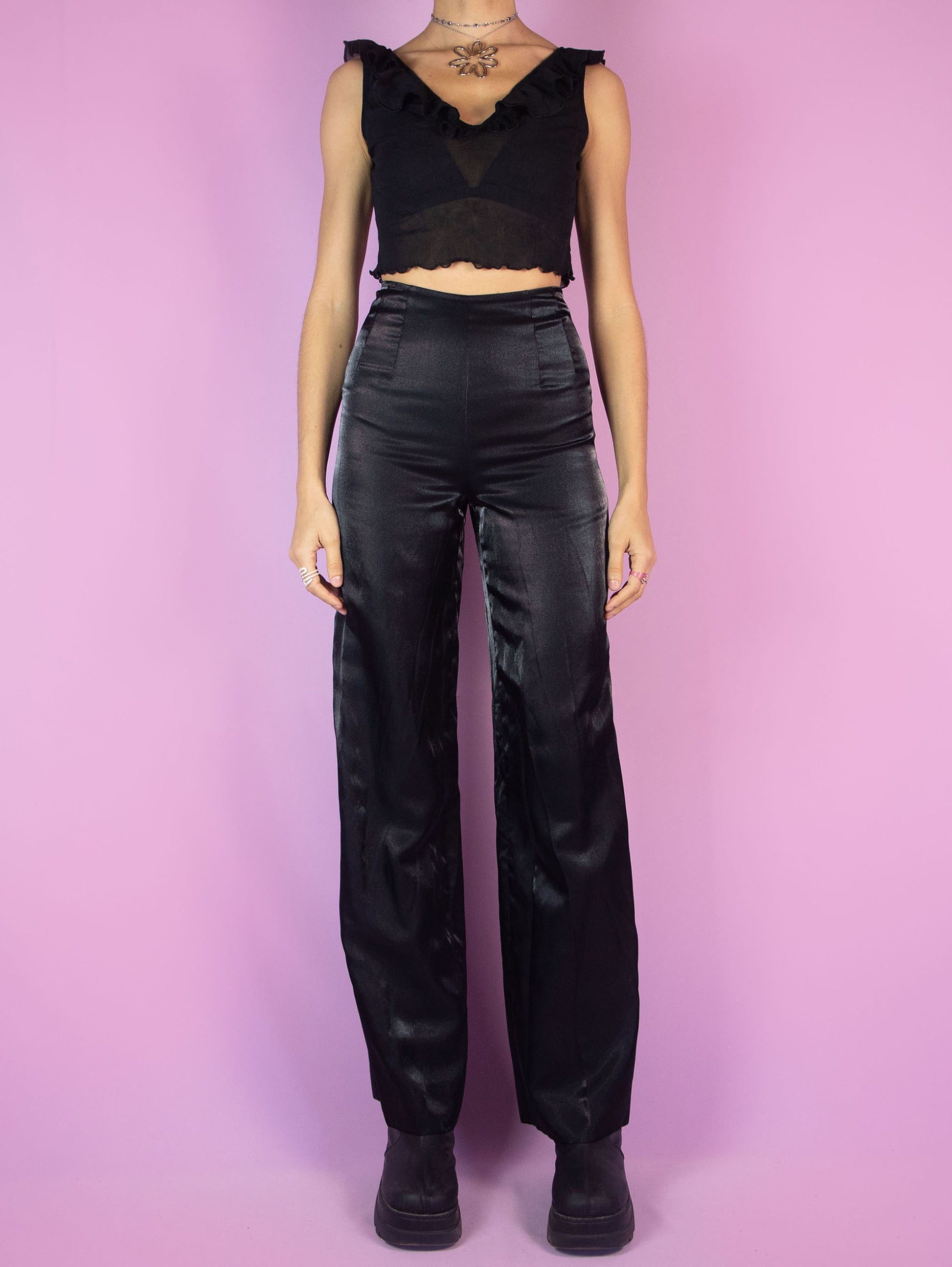 The Vintage 90s Black Tailored Wide Pants are shiny black iridescent pants with high-rise pleats, featuring a side zipper closure and wide legs. Elegant evening party 1990s classic pleated trousers.