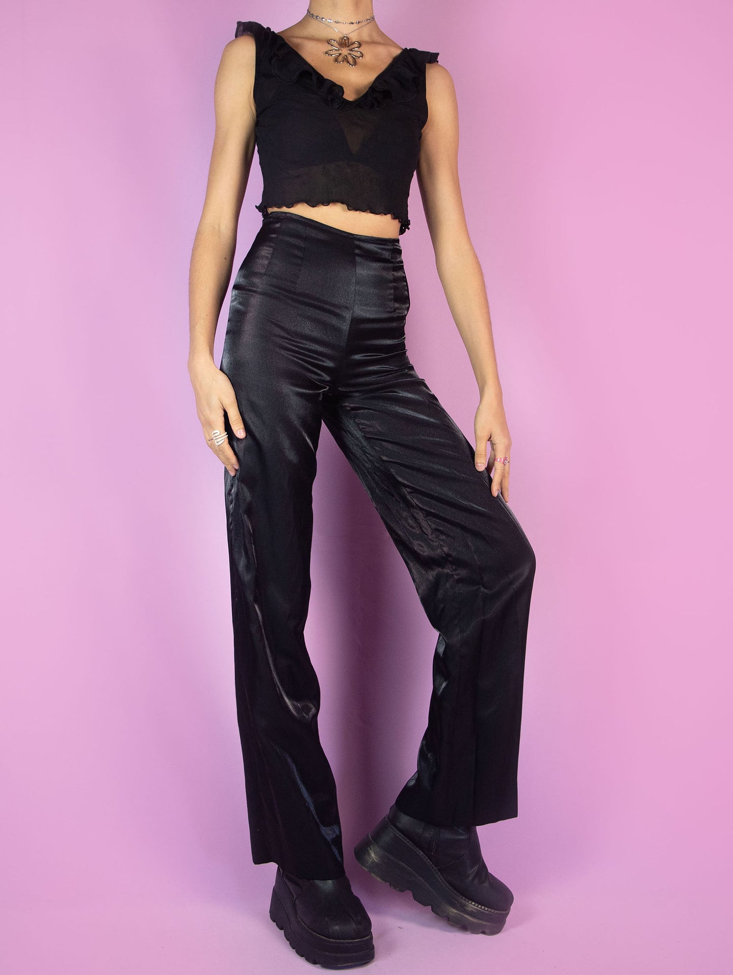 The Vintage 90s Black Tailored Wide Pants are shiny black iridescent pants with high-rise pleats, featuring a side zipper closure and wide legs. Elegant evening party 1990s classic pleated trousers.