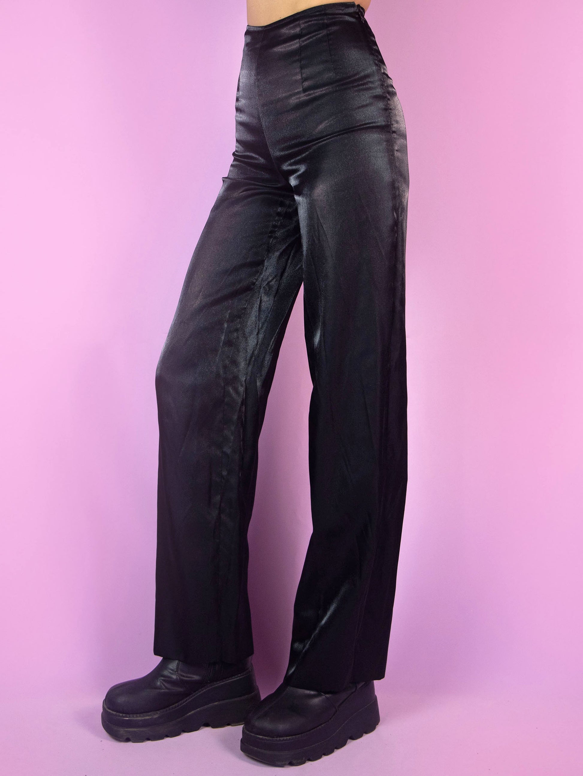 The Vintage 90s Black Tailored Wide Pants are shiny black iridescent pants with high-rise pleats, featuring a side zipper closure and wide legs. Elegant evening party 1990s classic pleated trousers.