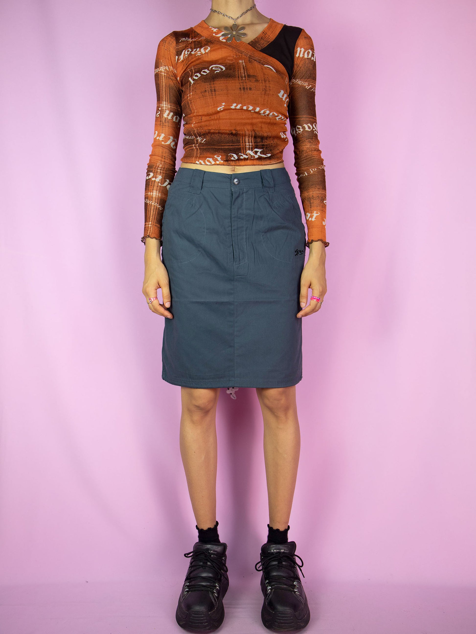 The Vintage Y2K Blue Utility Skirt is an asymmetric dark blue-gray cargo skirt equipped with pockets and a back slit, featuring a zipper. This cute cyber grunge gorpcore technical mini skirt perfectly captures the style of the 2000s.