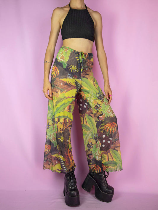 The Vintage Y2K Sheer Mesh Wide Pants are semi-sheer, tie-front mesh wide-leg trousers with a tropical floral landscape print. Beautiful summer beach festival pants from the 2000s.