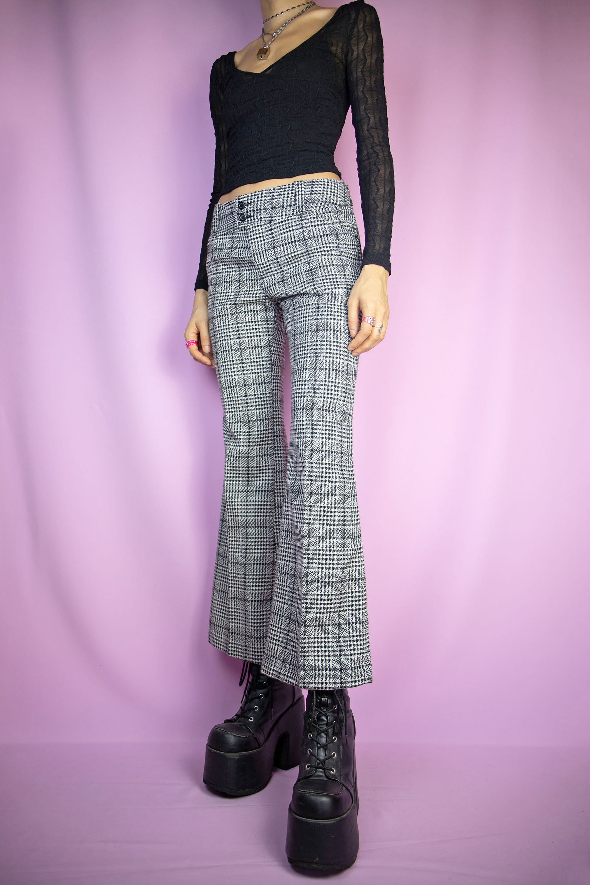 The Vintage 90s Plaid Flare Trousers are black and white checkered pattern pants with pockets, and a front zipper closure. Preppy office 1990s gingham knit tailored pants.