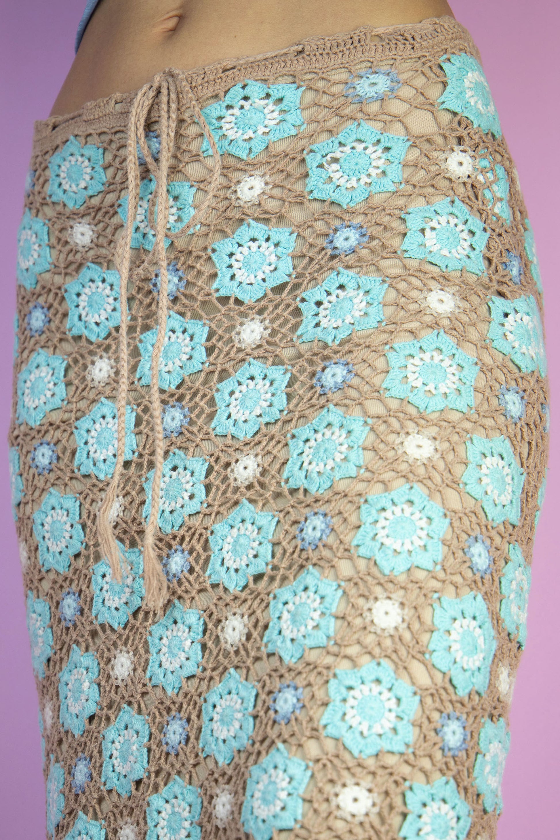 The Y2K Floral Crochet Knit Skirt is a vintage brown and blue knitted tie-front skirt. Boho 2000s summer mini skirt.