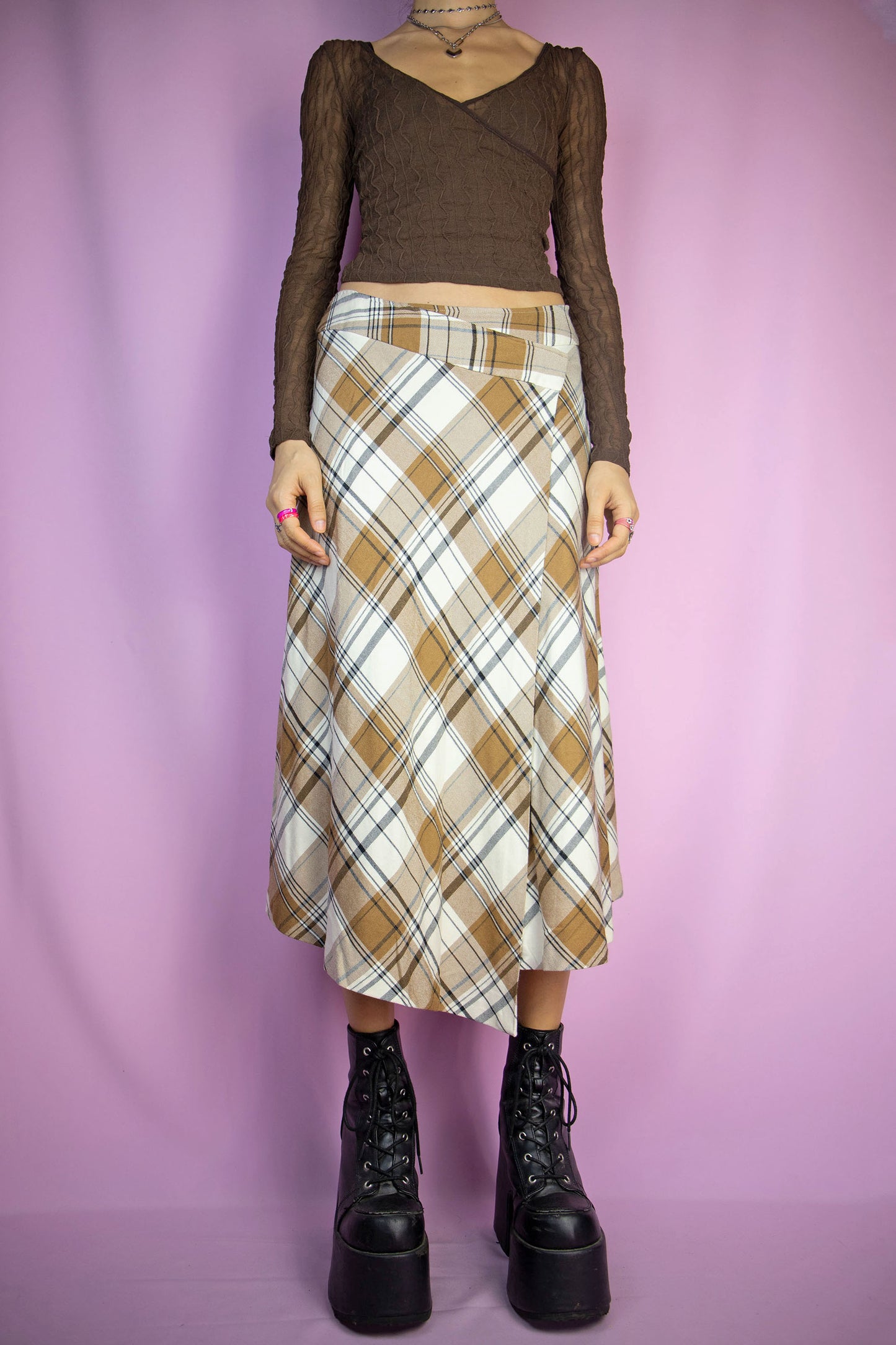 The Vintage Y2K Brown Plaid Midi Skirt is an asymmetrical wrap skirt in brown and beige checkered pattern, featuring a side zipper closure. This gorgeous piece reflects the dark academia preppy style and is a knit maxi skirt from the 2000s.