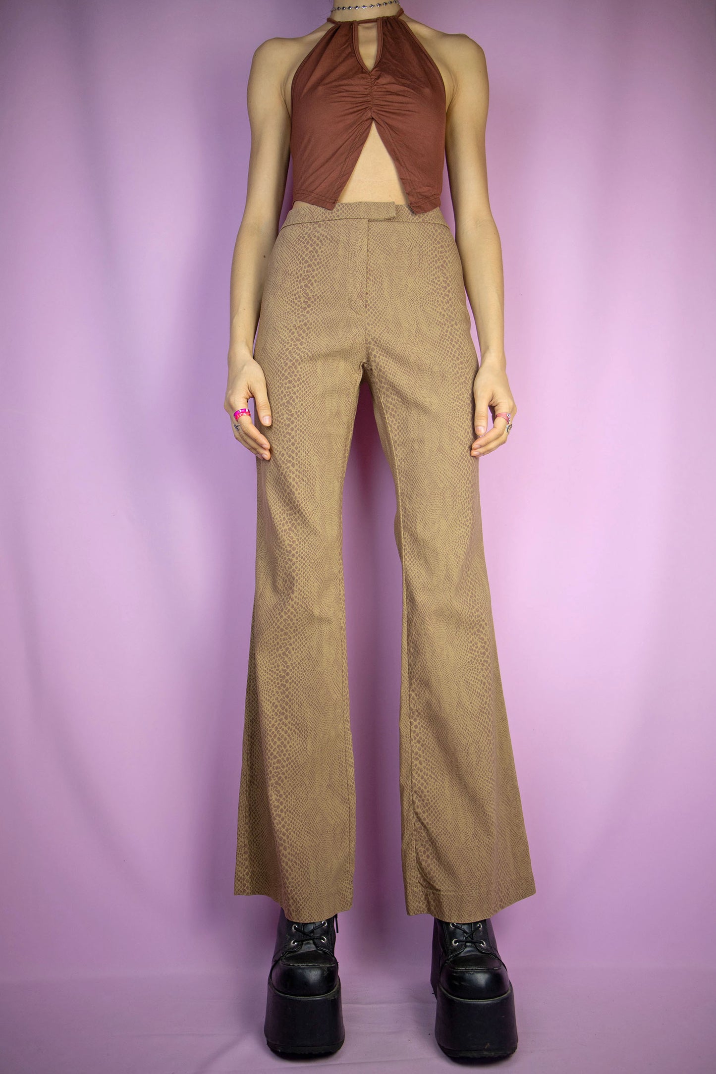 The Vintage Y2K Brown Croc Flare Pants feature a brown, stretchy fabric with a crocodile animal print and a front zipper closure. These iconic cyber party night festival trousers capture the flair of the 2000s.