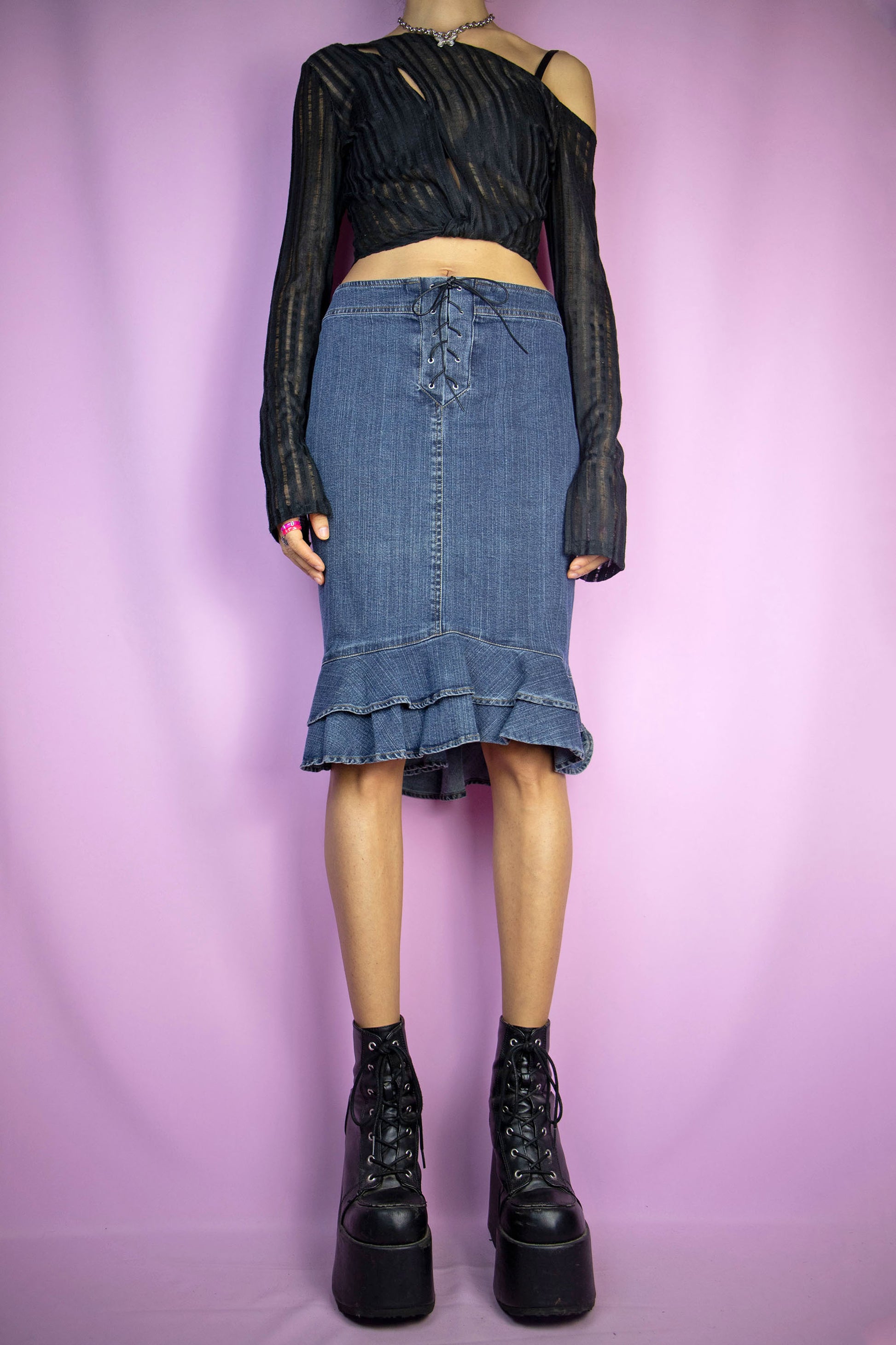 The Vintage Y2K Ruffle Hem Denim Skirt is a sleek dark denim trumpet skirt with a charming ruffled hem, back zipper closure, and lace-up tie front. This iconic cyber pencil jean mini skirt captures the essence of 2000s fashion.