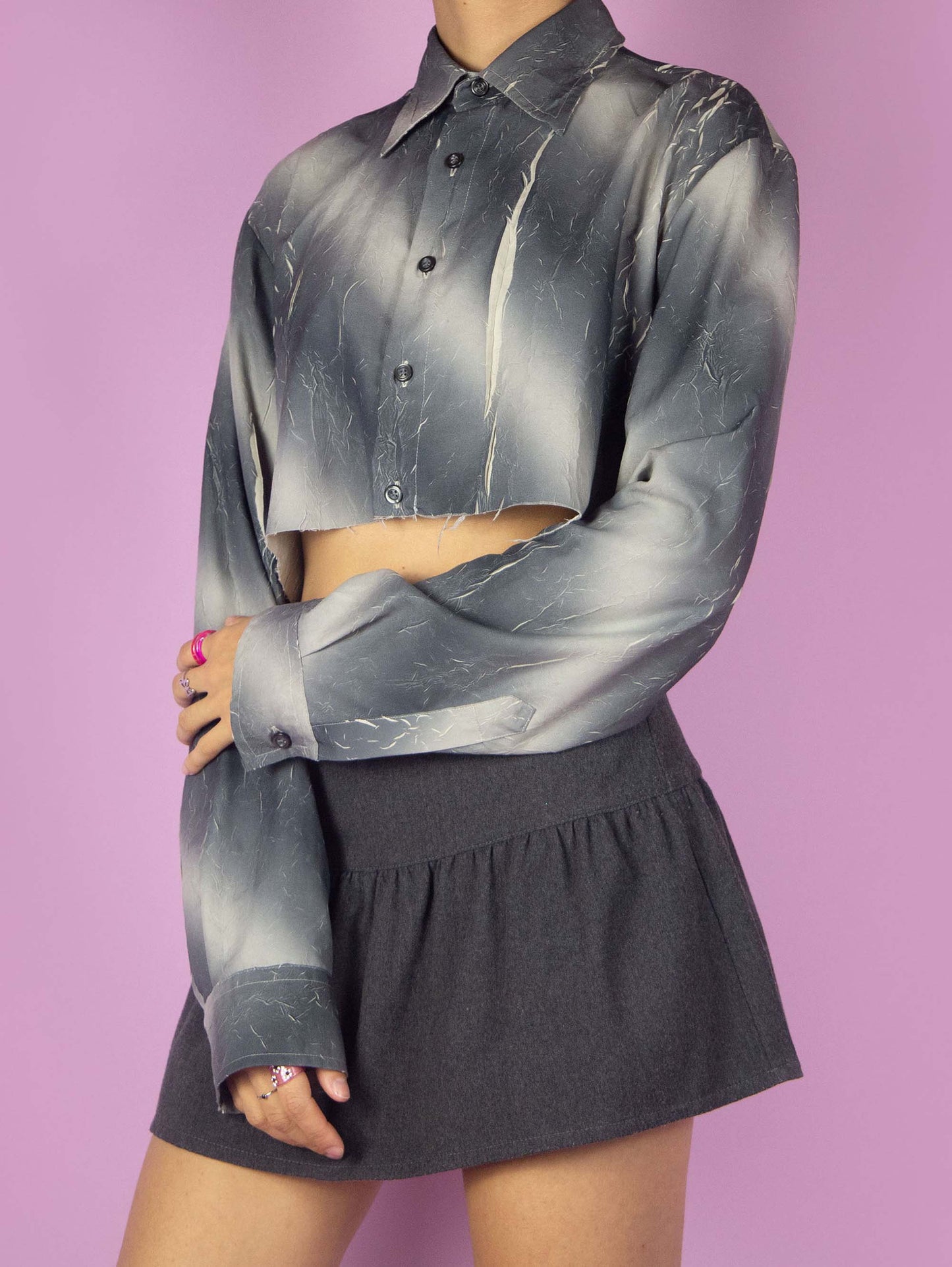 The Y2K Subversive Gray Cropped Shirt is a vintage blouse featuring a gray and beige tie-dye ombre print with a textured wrinkled effect, and it has a raw hem. Cyber deconstructed 2000s crop top.