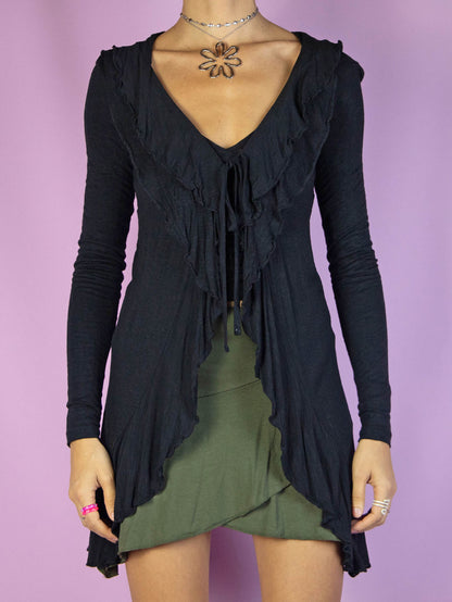 The Y2K Black Ruffle Tie Top is a vintage long-sleeve black top with ruffles and tied at the front. Gorgeous 2000s fairy grunge whimsygoth cardigan.