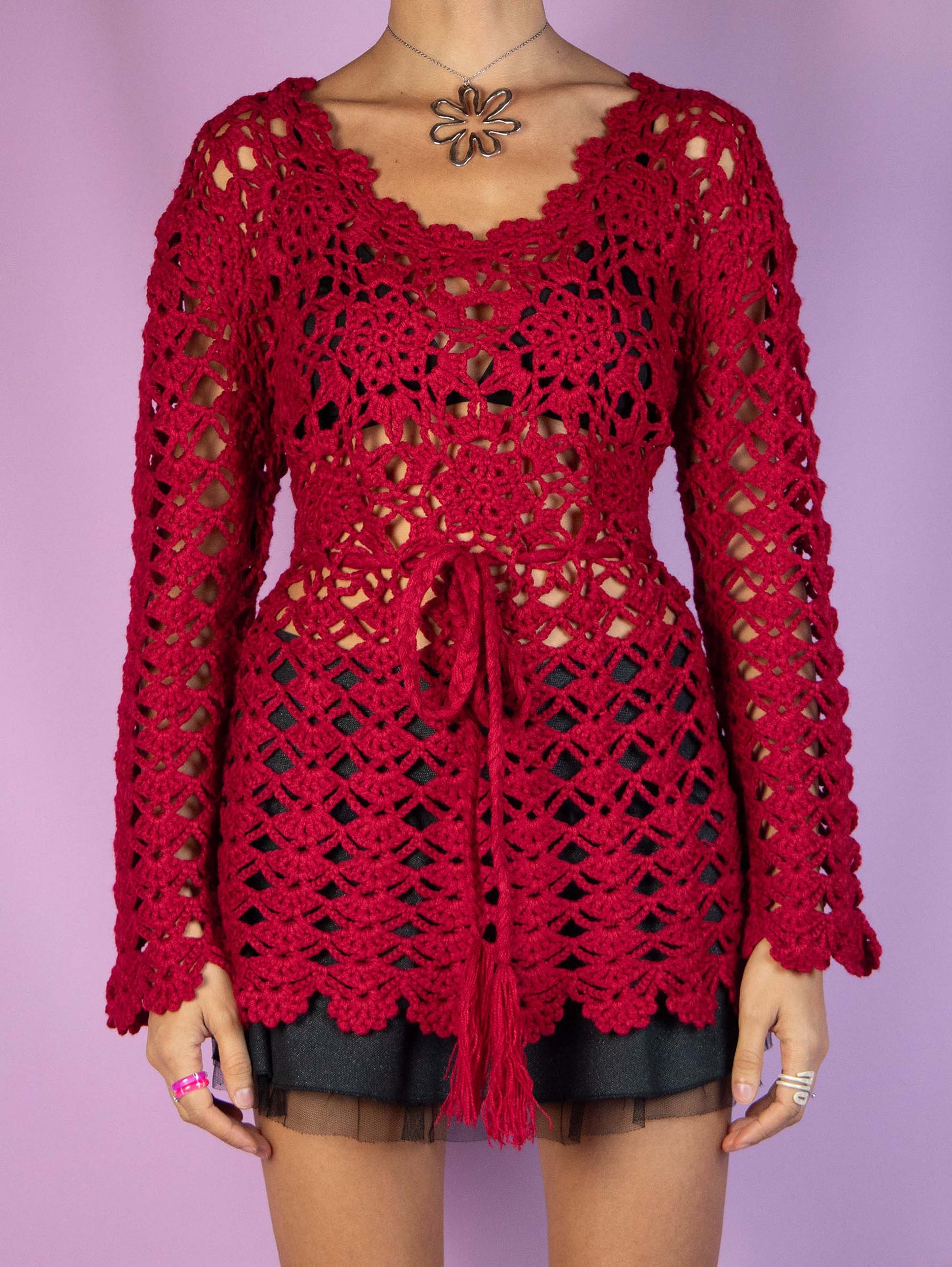 The Y2K Red Crochet Knit Sweater is a red crocheted knit top that ties at the waist and is made from a wool blend. Stunning romantic coquette boho 2000s pullover.