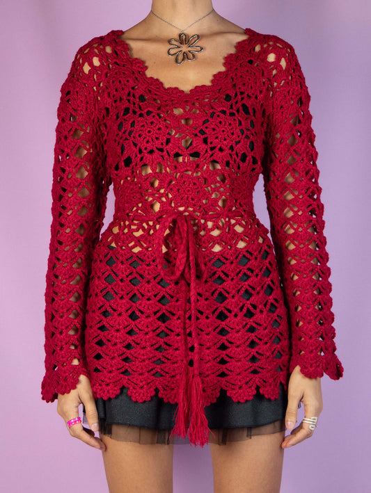 The Y2K Red Crochet Knit Top is a vintage 2000s romantic boho style crocheted pullover sweater that ties at the waist and is made from a wool blend. Excellent vintage condition.