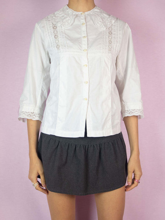 The Vintage White Cotton Collar Blouse is a half-sleeve summer pleated shirt in a country cottage prairie style with button closure and lace details.