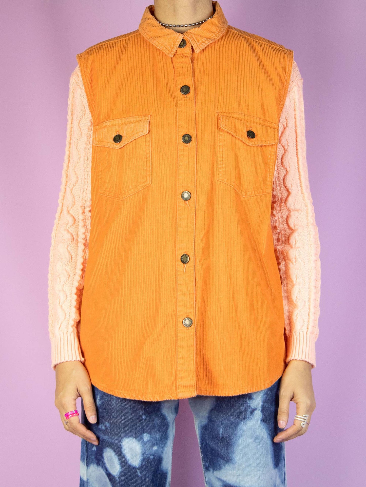 The Vintage 90s Orange Corduroy Vest Jacket is an orange corduroy vest with a collar, pockets, and button closure. Retro grunge 1990s utility jacket.