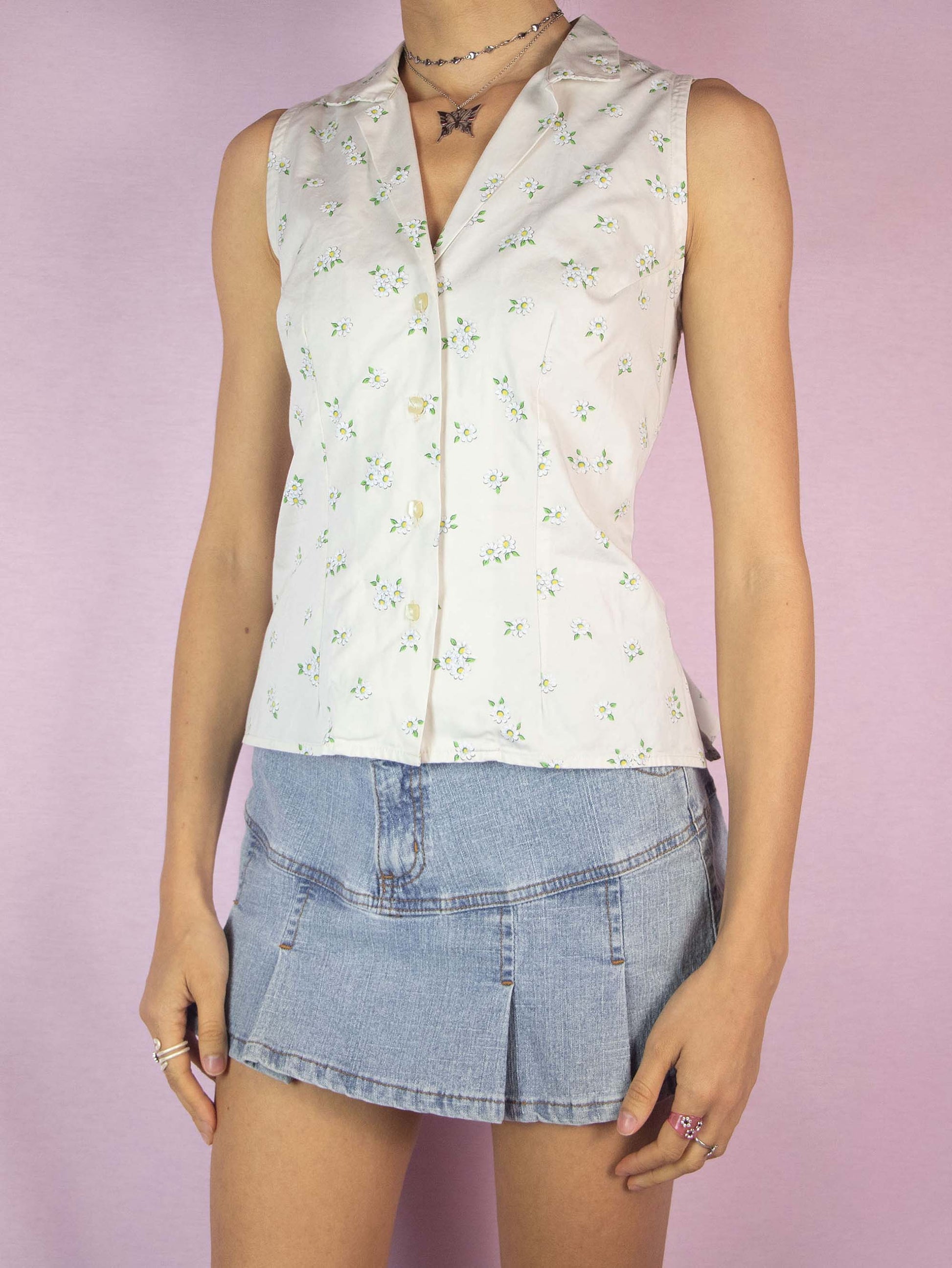 The Vintage 90s Sleeveless Floral Print Blouse is a boho cottage prairie summer off-white shirt with a daisy pattern, collar, and buttons.