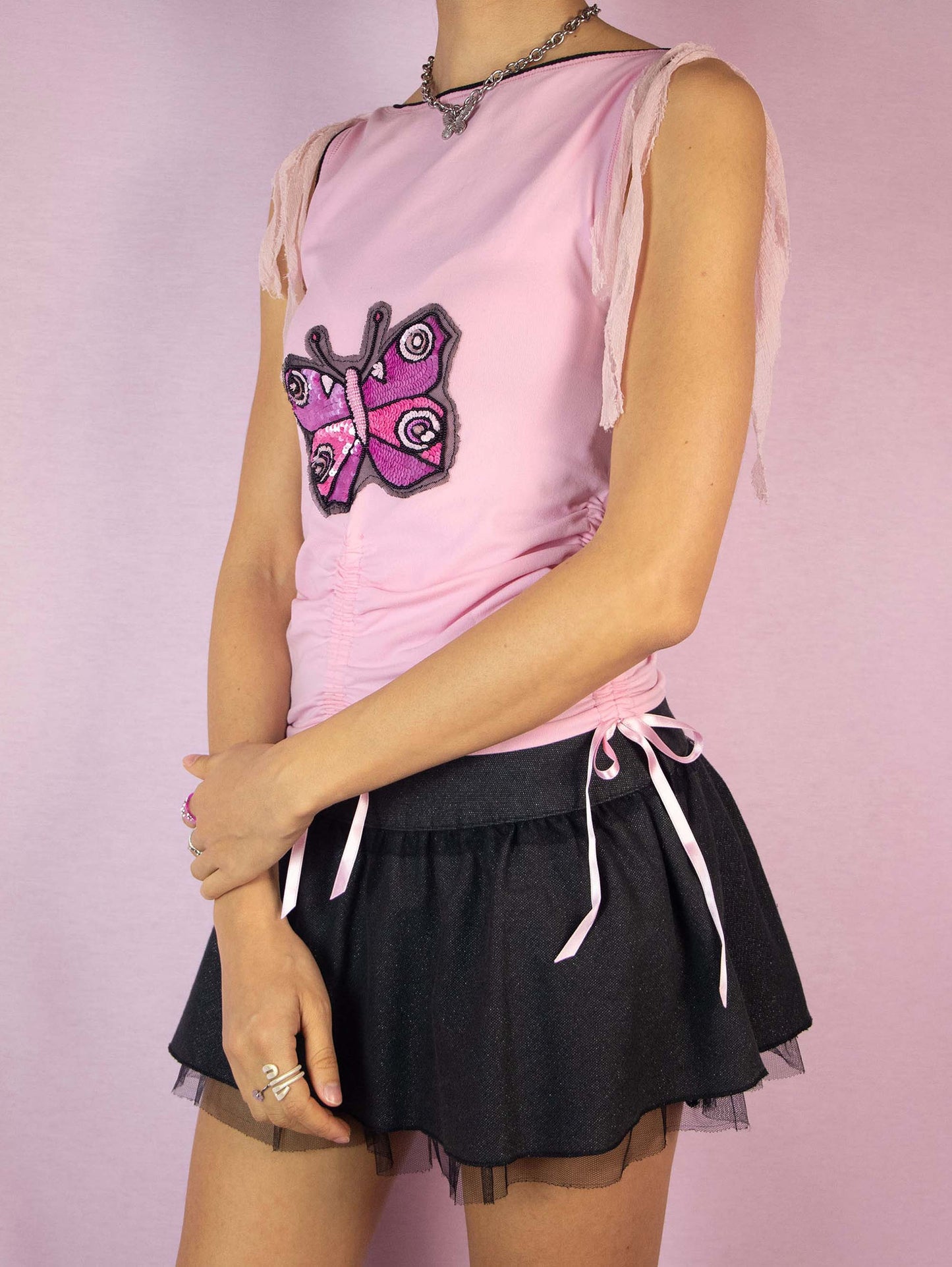 The Y2K Pink Sleeveless Ruched Top is a vintage 2000s elastic top for summer festival parties, light pastel pink, embellished with sequins and beads, and with bow details that tie. Made in Italy.