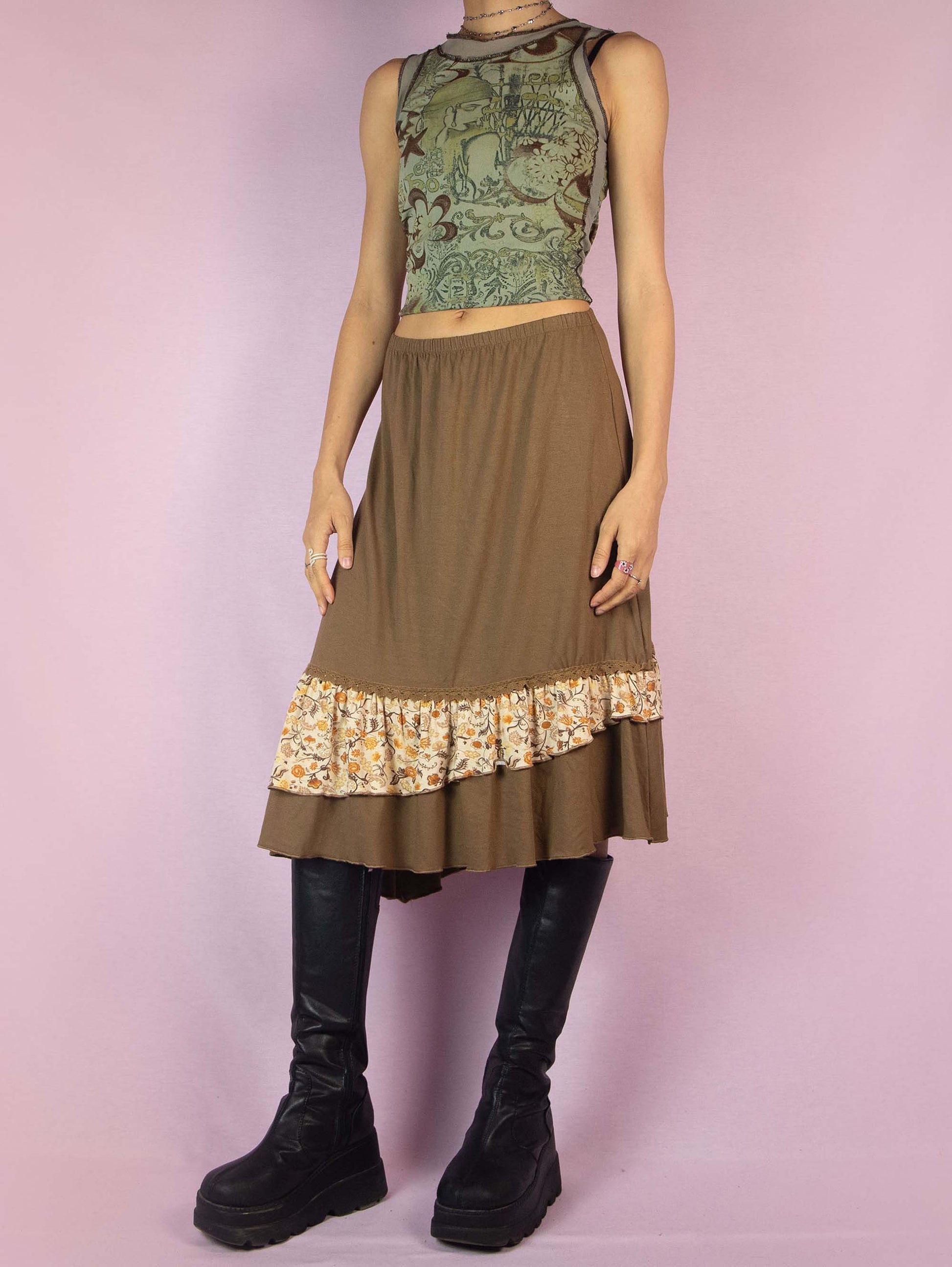 The Y2K Asymmetric Brown Midi Skirt is a vintage 2000s piece featuring an asymmetrical ruffle hem adorned with a floral print and an elastic waist. Perfect for a whimsical and casual spring outfit.