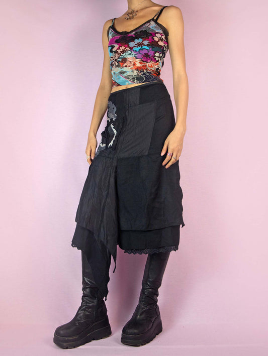 Y2K Black Asymmetrical Layered Skirt is a vintage 2000s subversive deconstructed fairy goth-inspired midi skirt with embroidered applique details and a side zipper closure.