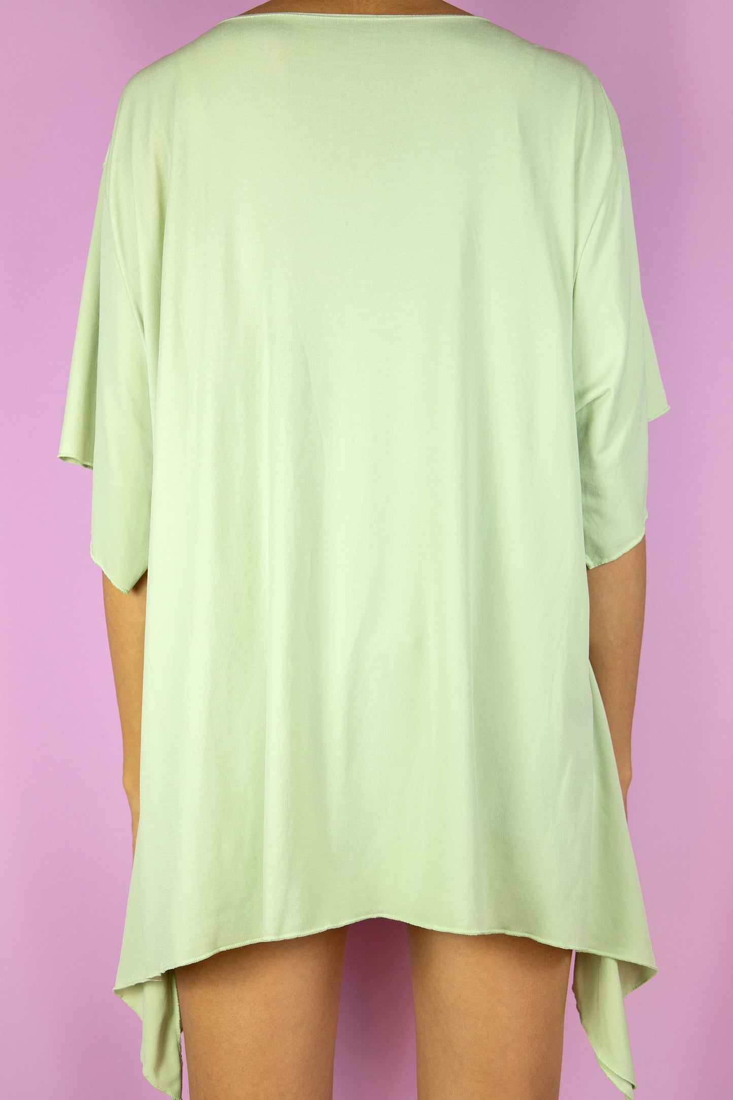 The Y2K Green Asymmetrical Top is a vintage pastel light green short sleeve shirt with an asymmetric pointed hem and an o-ring detail. Cyber fairy grunge 2000s summer top.