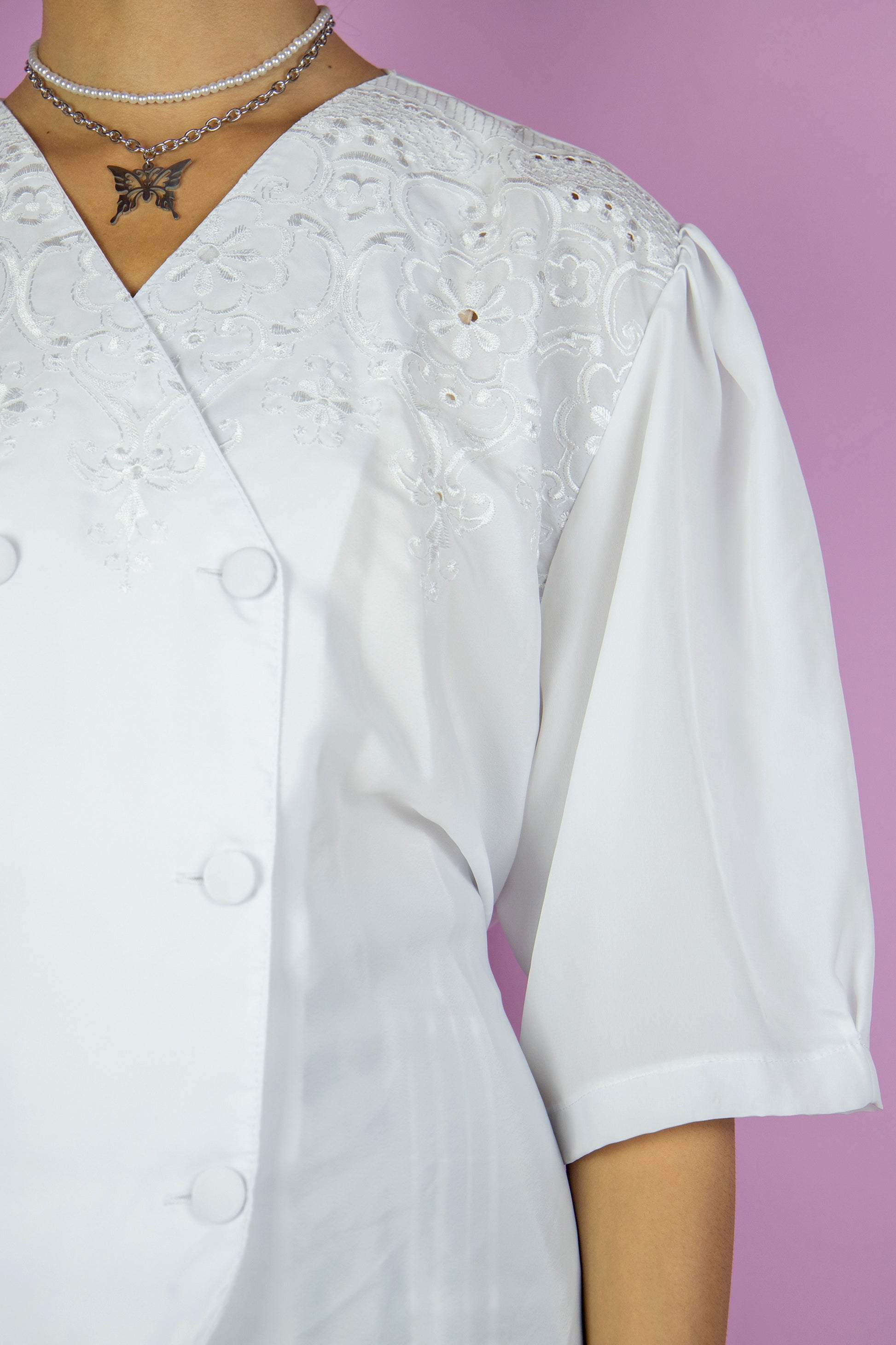 The Vintage 90s White Cottage Blouse is a semi-sheer top with short puff sleeves, a double row of buttons on the front, embroidered details and is tied at the back. Romantic country prairie 1990s boho summer shirt.