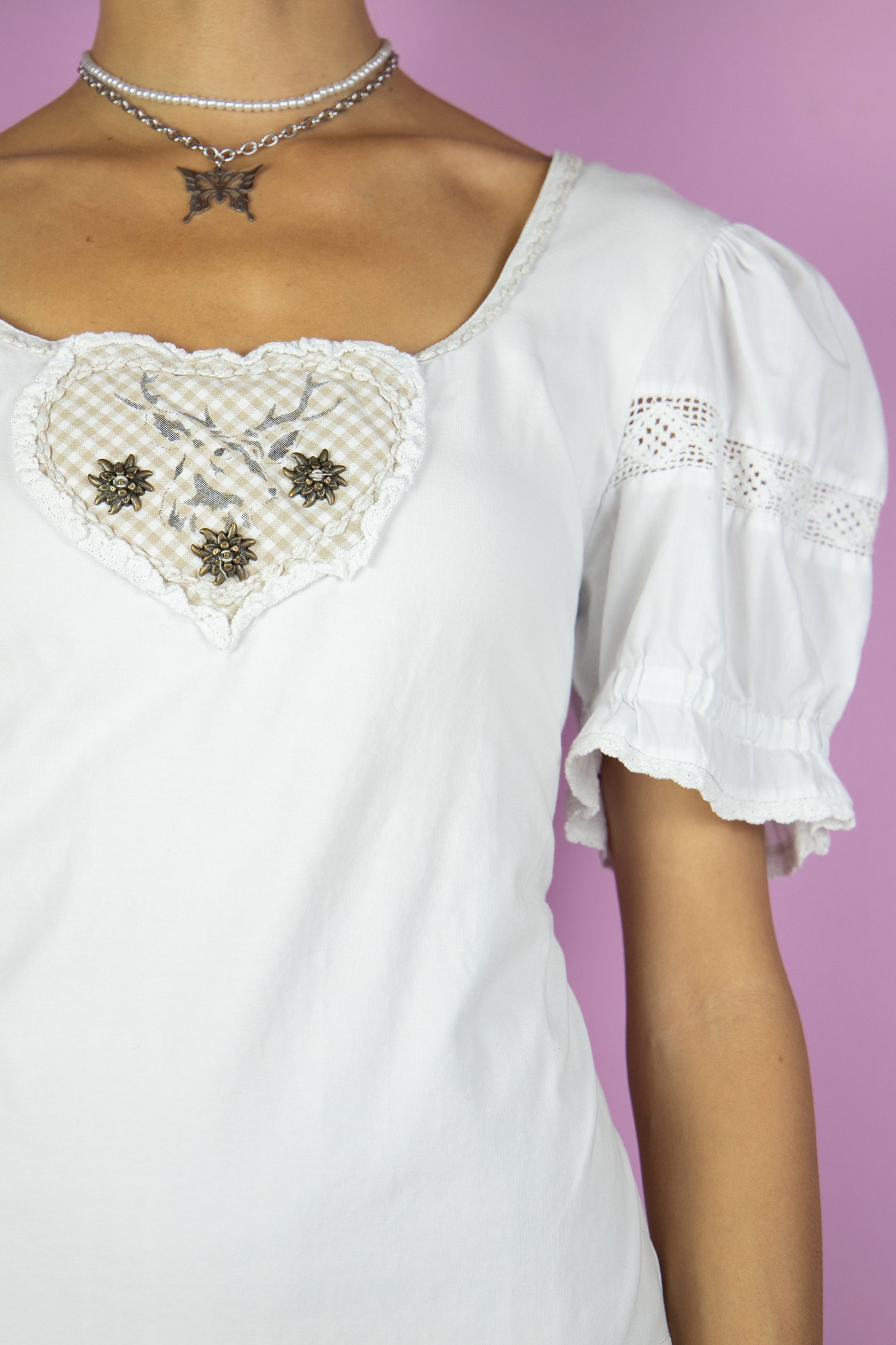 The Vintage 90s White Cottage Milkmaid Top is a short puff sleeve top with crochet details and checkered heart on the front. Country prairie inspired 1990s shirt.