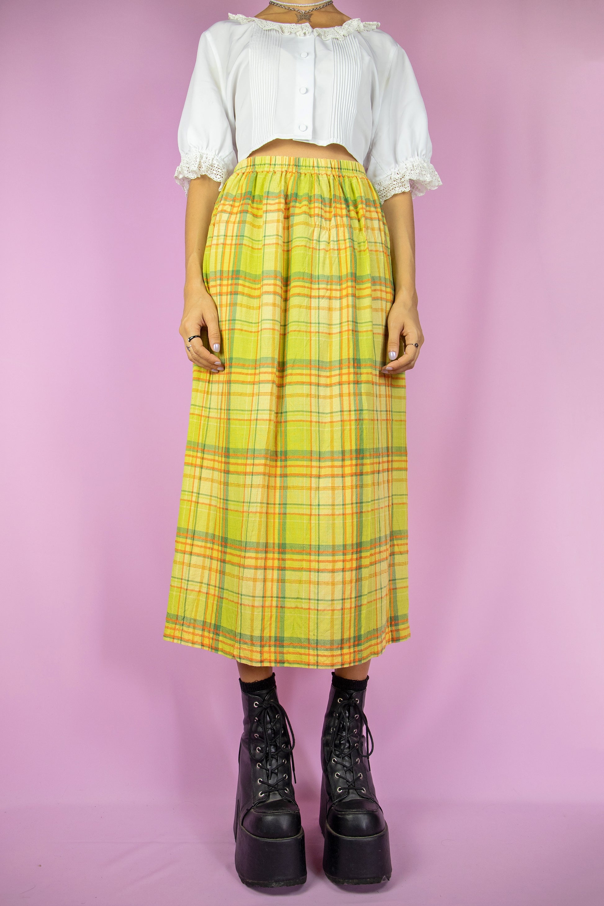 The Vintage 90’s Green Plaid Midi Skirt is a long, green, yellow, and orange checkered skirt featuring a side slit and elastic waist. This super cute boho skirt draws inspiration from cottage prairie style, reminiscent of the 1990s.